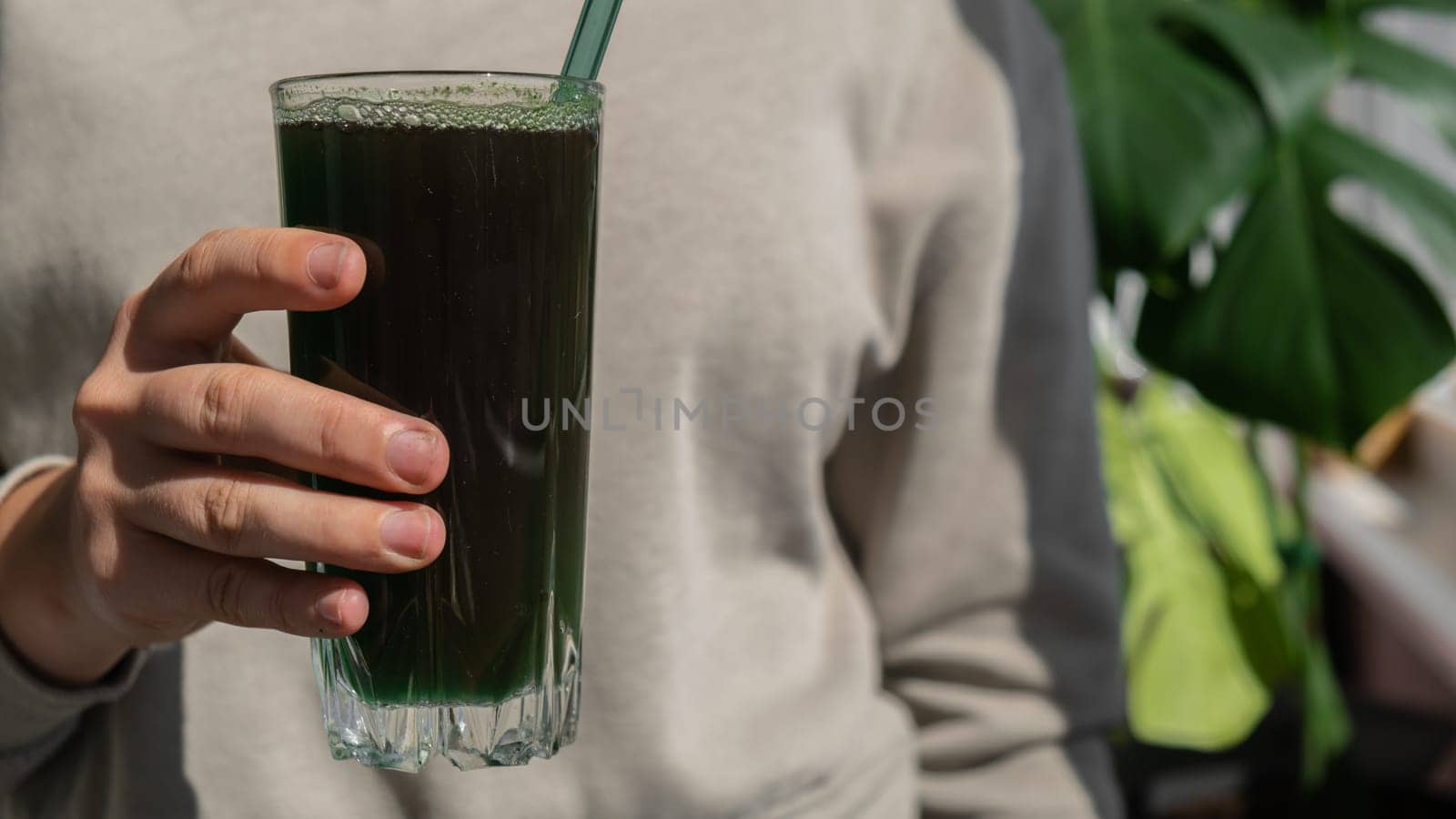 Unrecognizable woman drinking Natural organic green spirulina algae powder drink on neutral beige background. Chlorella seaweed vegan superfood cocktails smoothie supplement source and detox drinking. Innovative ingredient functional environmentally friendly food. Copy space Healthy nutritional antioxidant concept.