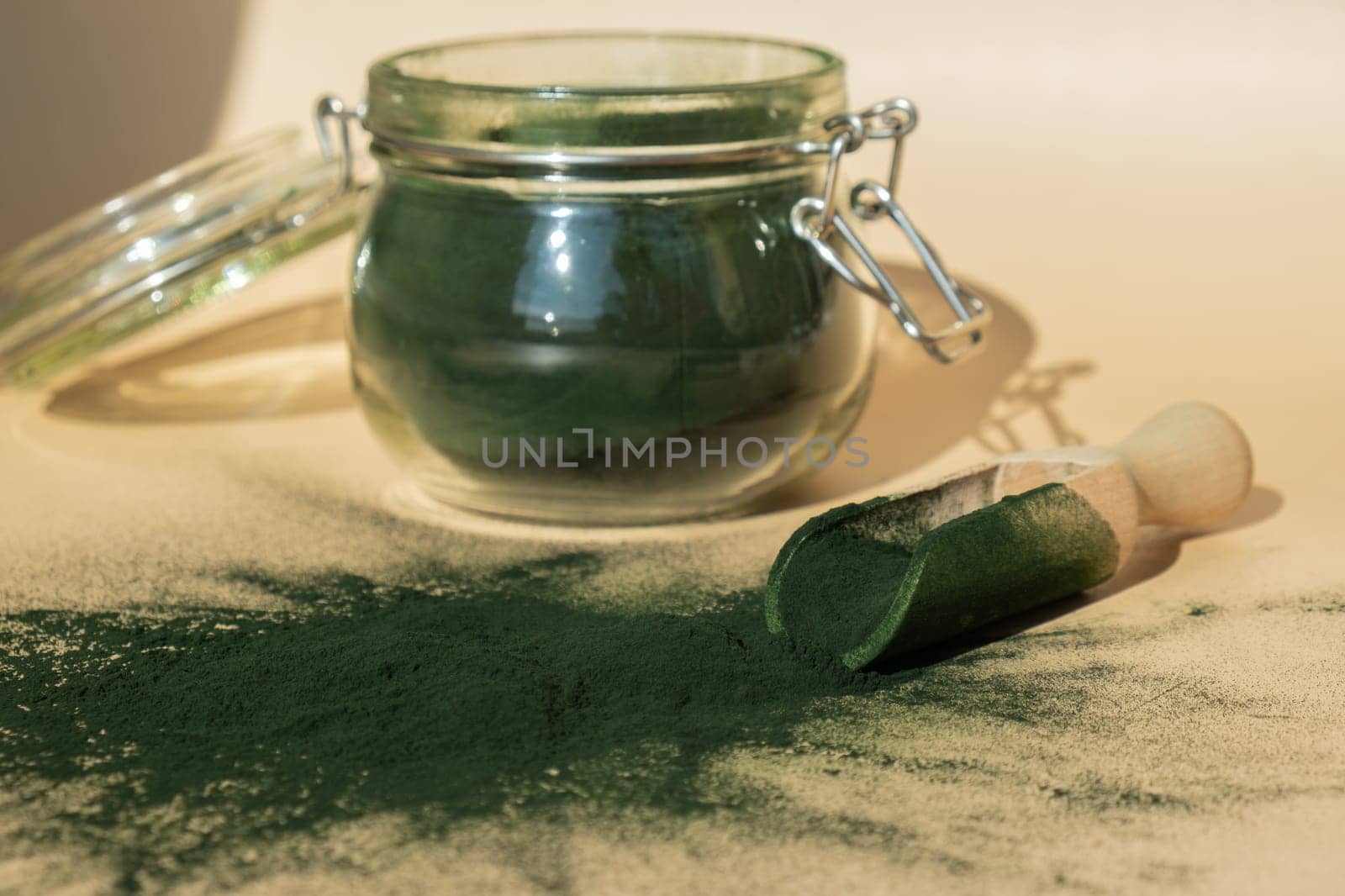 Organic blue-green algae spirulina powder food in glass jar with wooden spoon. Health benefits of spirulina chlorella. Vitamins and minerals to diet. Detox dietary supplement Seaweed superfood by anna_stasiia