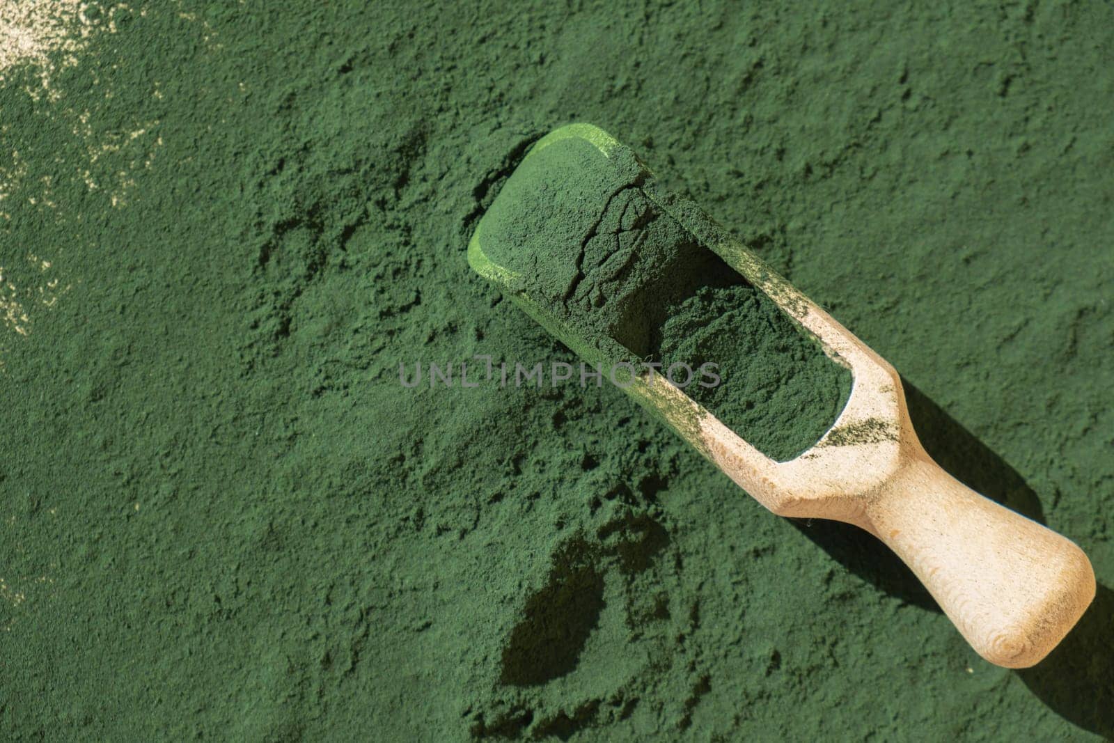 Natural organic green spirulina algae powder in wooden spoon on neutral background. Chlorella seaweed vegan superfood supplement source and detox. Copy space Healthy nutritional antioxidant concept