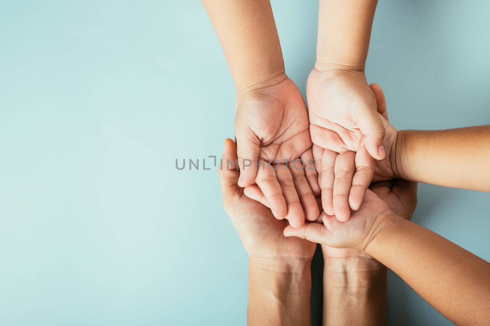 Family top view hands stacked on isolated background. Parents and kid hold empty space expressing support and love for Family and Parents Day.