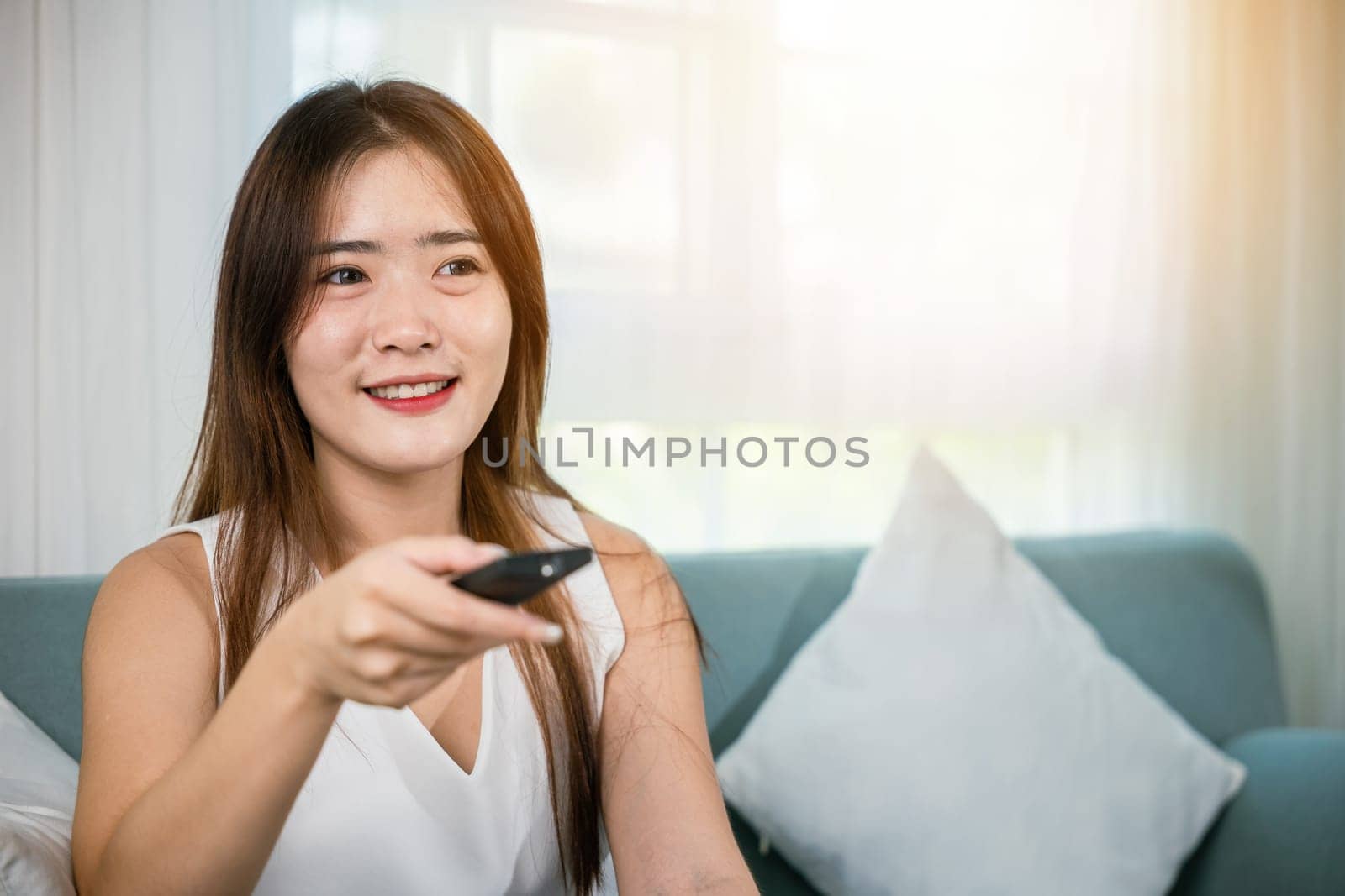 Beautiful female person look movie holding remote controller watching television, woman smiling sit relaxing watch TV hold remote control looking news on sofa in living room, entertainment lifestyles