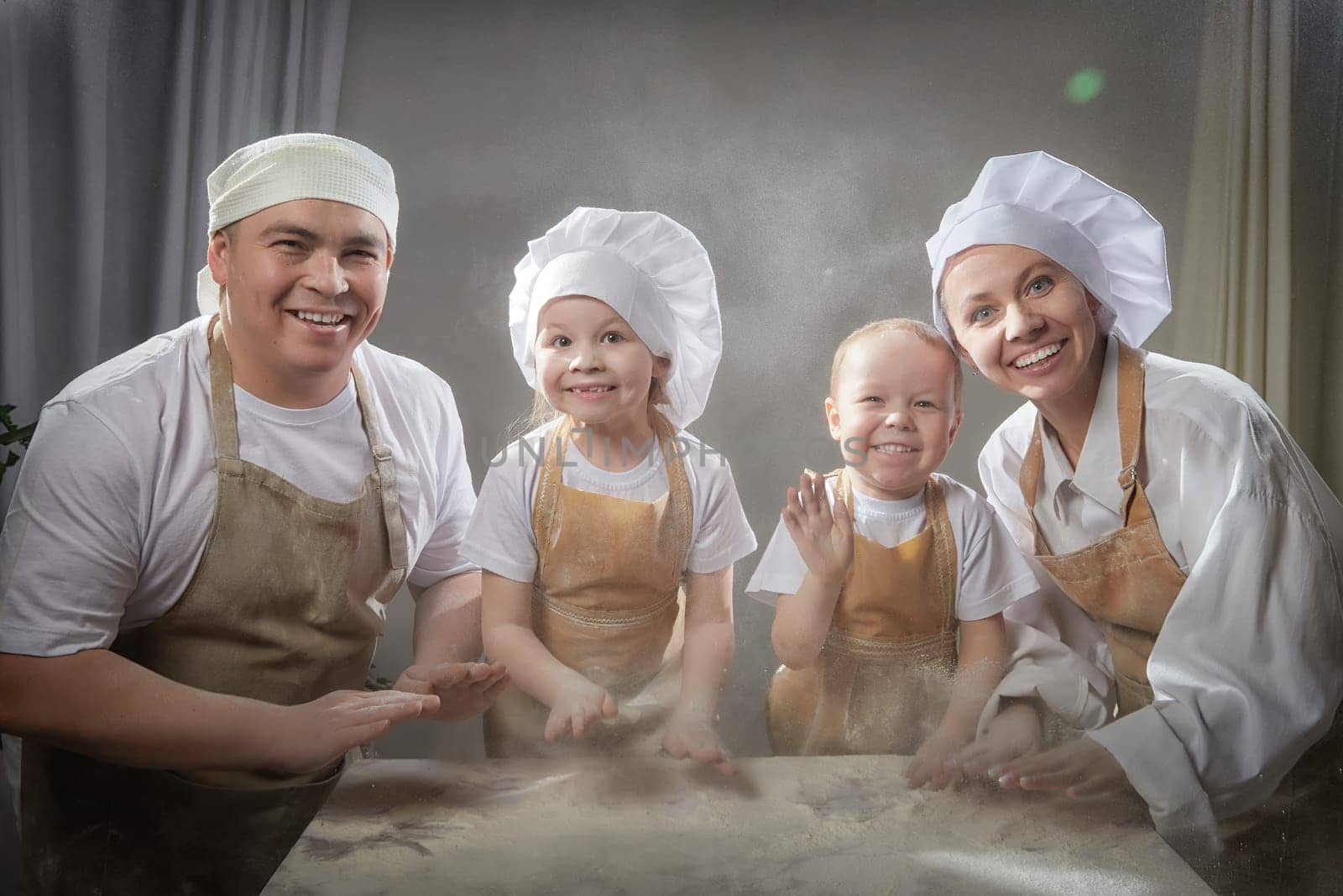 Cute oriental family with mother, father, daughter, son cooking in kitchen on Ramadan, Kurban-Bairam, Eid al-Adha. Funny family at photo shoot. Easter by keleny
