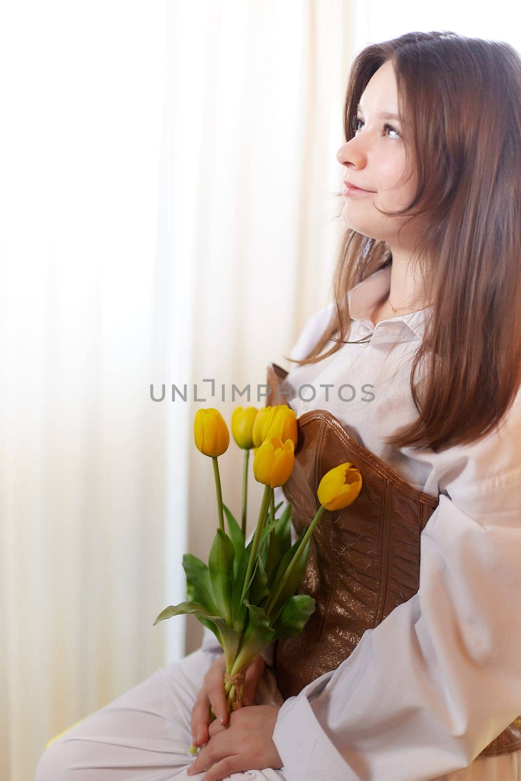 Beautiful sweet girl in nightgown in early morning with bouquet of delicate yellow tulips. Gift on International Women's Day on March 8th. Cosmetics, skin and hair care. Perfume, natural fragrance