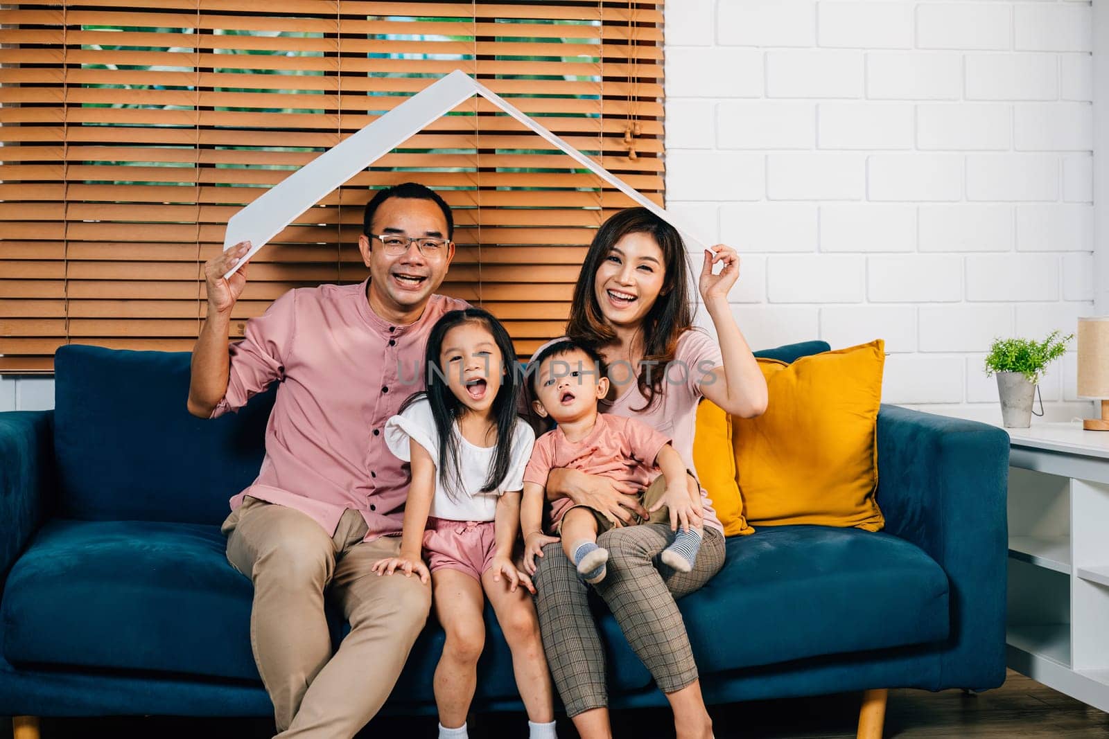 A joyful family enjoys the warmth of their cozy living room holding a cardboard roof mockup symbolizing protection and planning during their home relocation. Safety and togetherness is the answer.