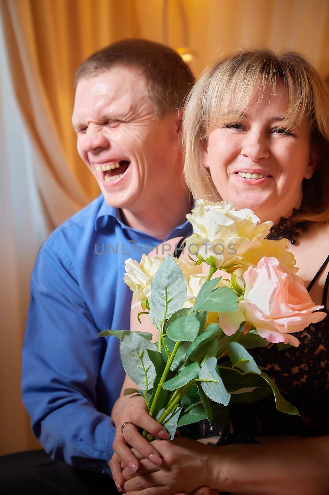 A plump woman in royal dress and a skinny man together in honeymoon hotel room. An adult newlywed couple embraces in an intimate setting. Queen Girl and guy in love