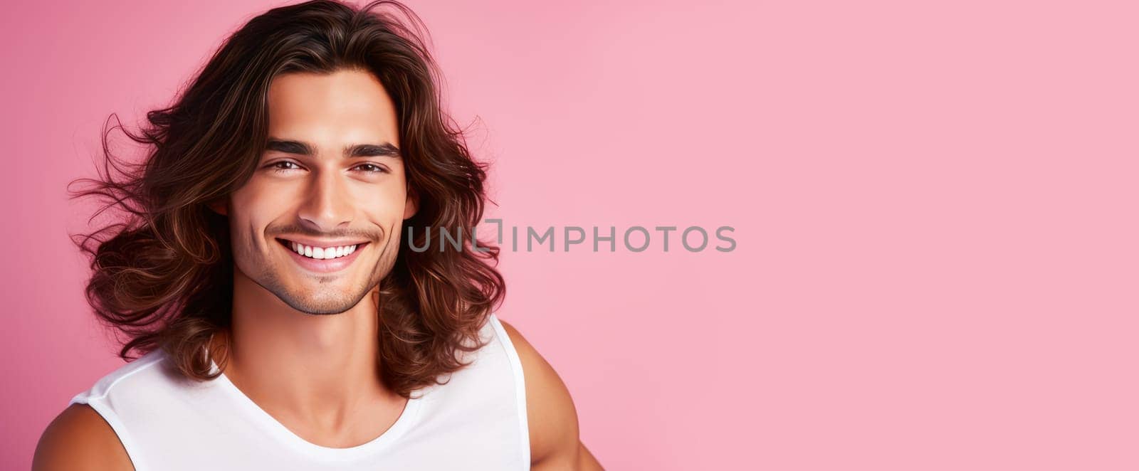 Portrait of an elegant sexy smiling Latino man with perfect skin and long hair, on a pink background. Advertising of cosmetic products, spa treatments shampoos and hair care products, dentistry and medicine, perfumes and cosmetology for men