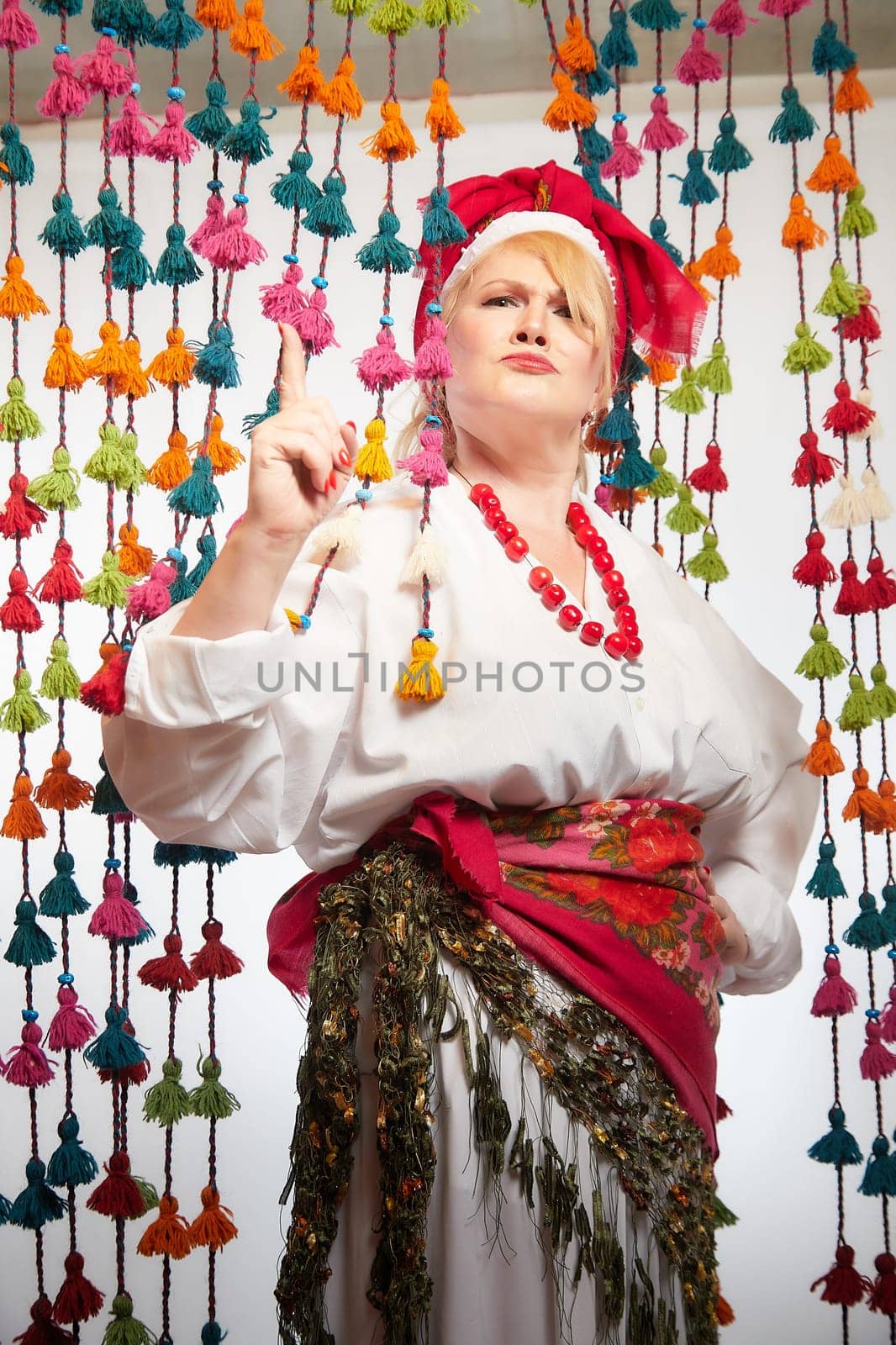 Portrait of cheerful funny adult mature woman solokha. Female model in clothes of national ethnic Slavic style. A stylized Ukrainian, Belarusian or Russian woman poses in a comic photo shoot