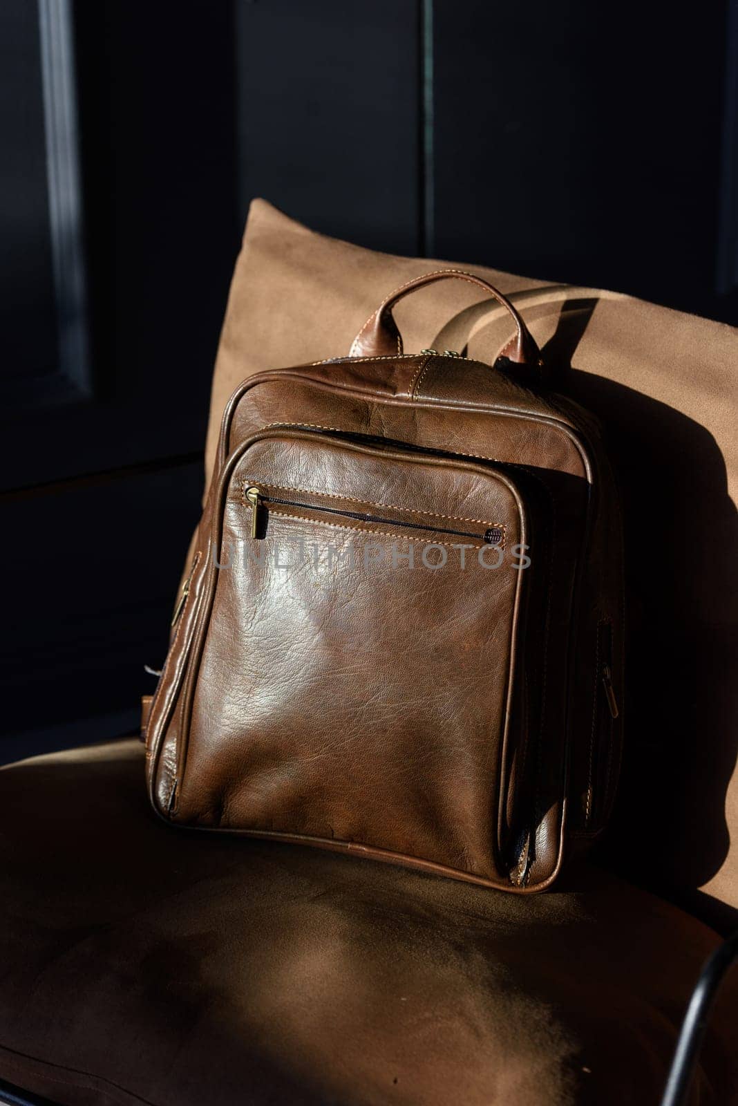 Brown leather backpack on chair, close up..