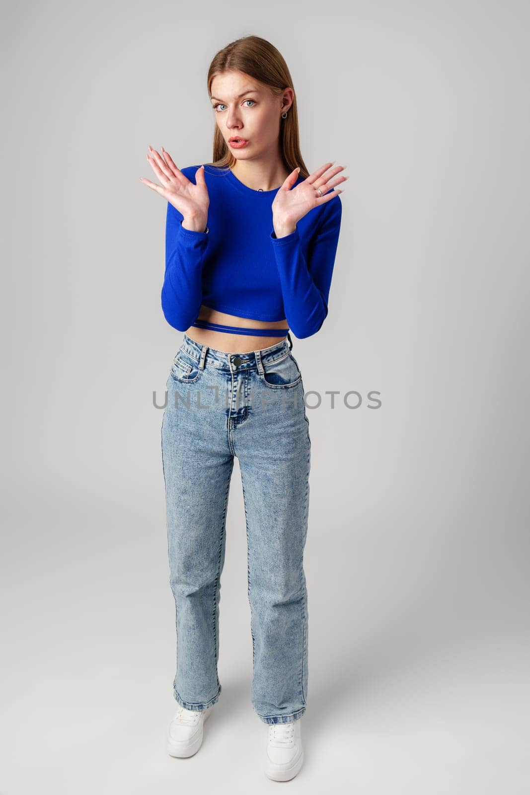 Young Woman in Blue Top Holding Out Hands in studio