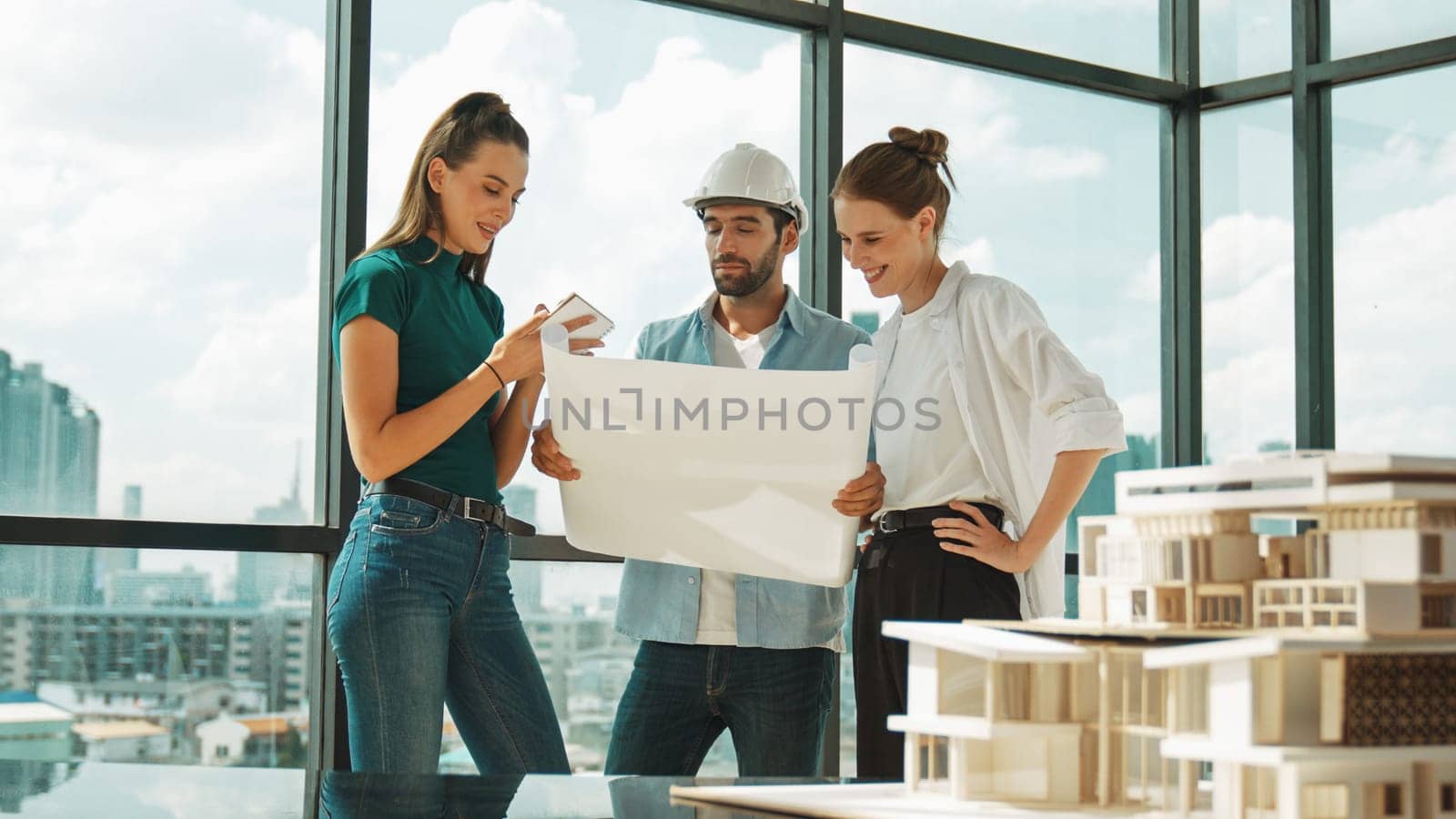 Professional architect engineer team talking, sharing, brainstorming about design while manager hold at project plan. Young architect holding plan while manager listen and point at plan. Tracery