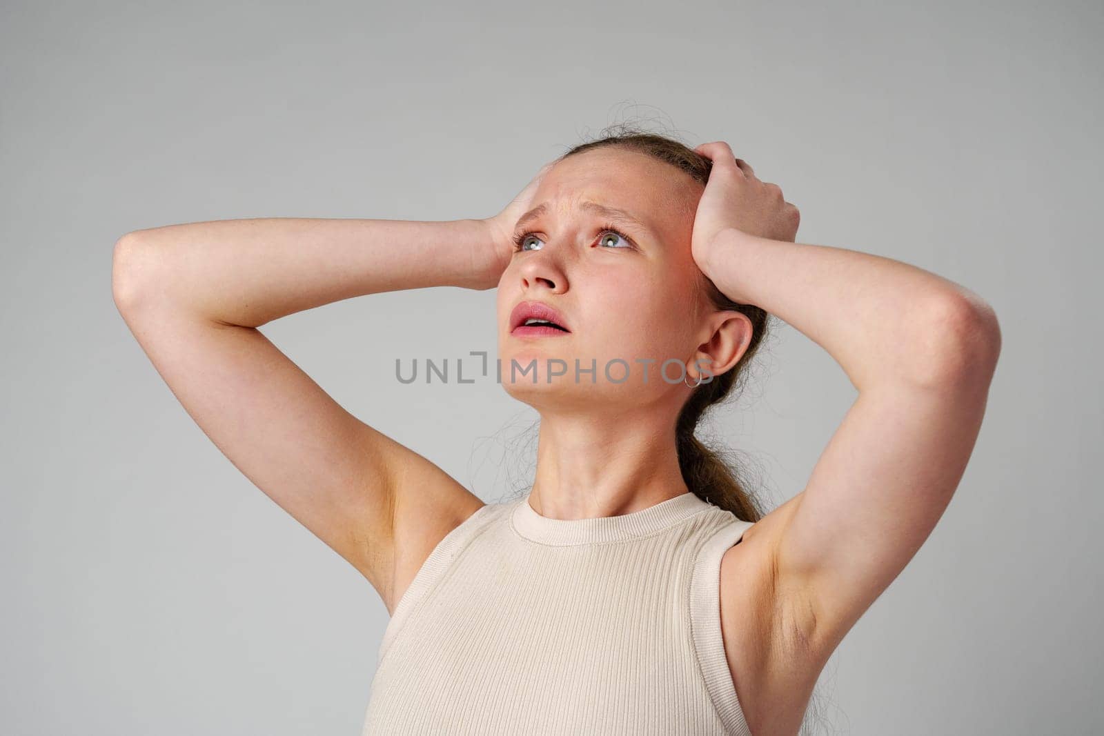 Young Woman Holding Head in Hands in studio close up