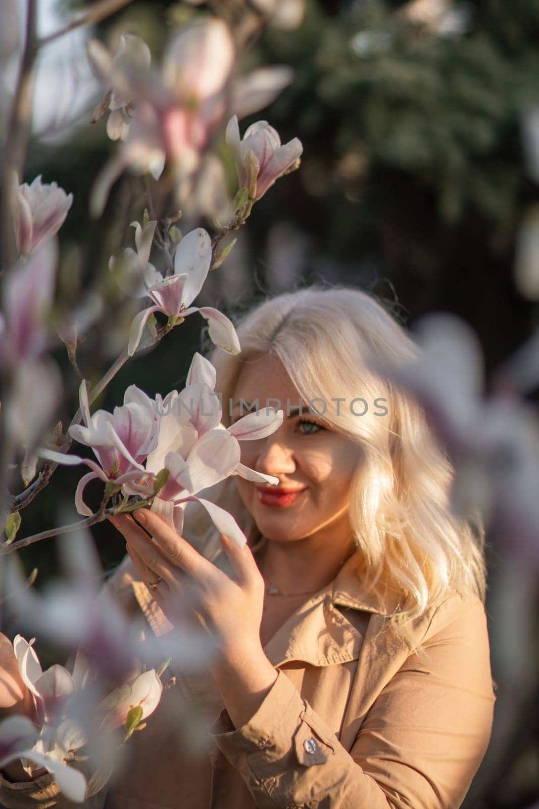 Magnolia flowers woman. A woman is holding a magnolia flower in her hand and standing in front of a tree. Concept of serenity and beauty, as the woman is surrounded by nature and the flower adds a touch of color