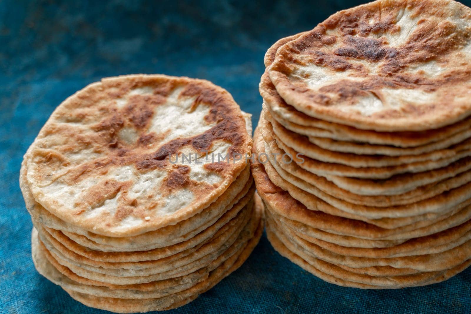 Flatbread lavash, chapati, naan, heap of tortilla on a blue background Homemade flatbread stacked