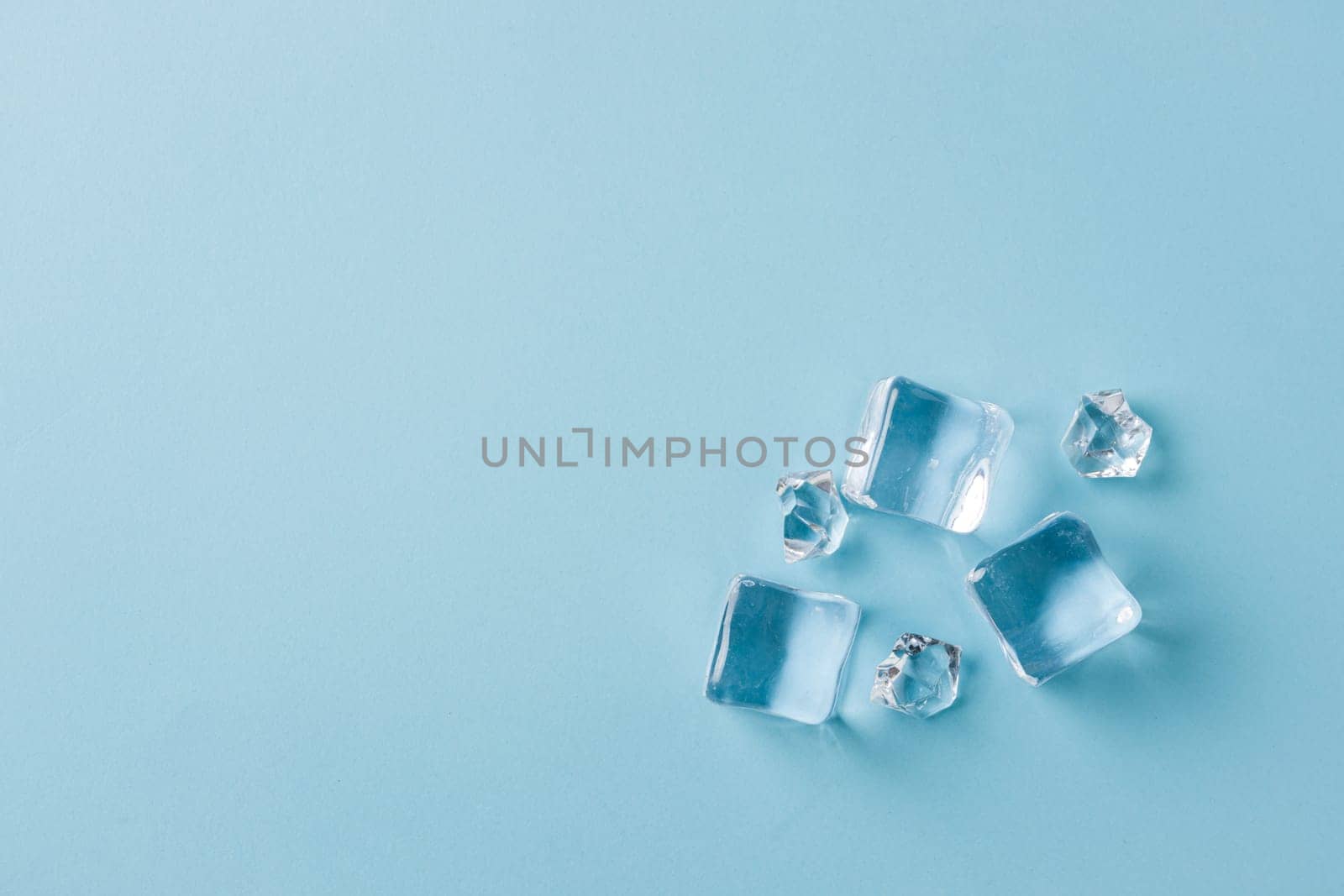 top view of ice cubes of different sizes on blue background