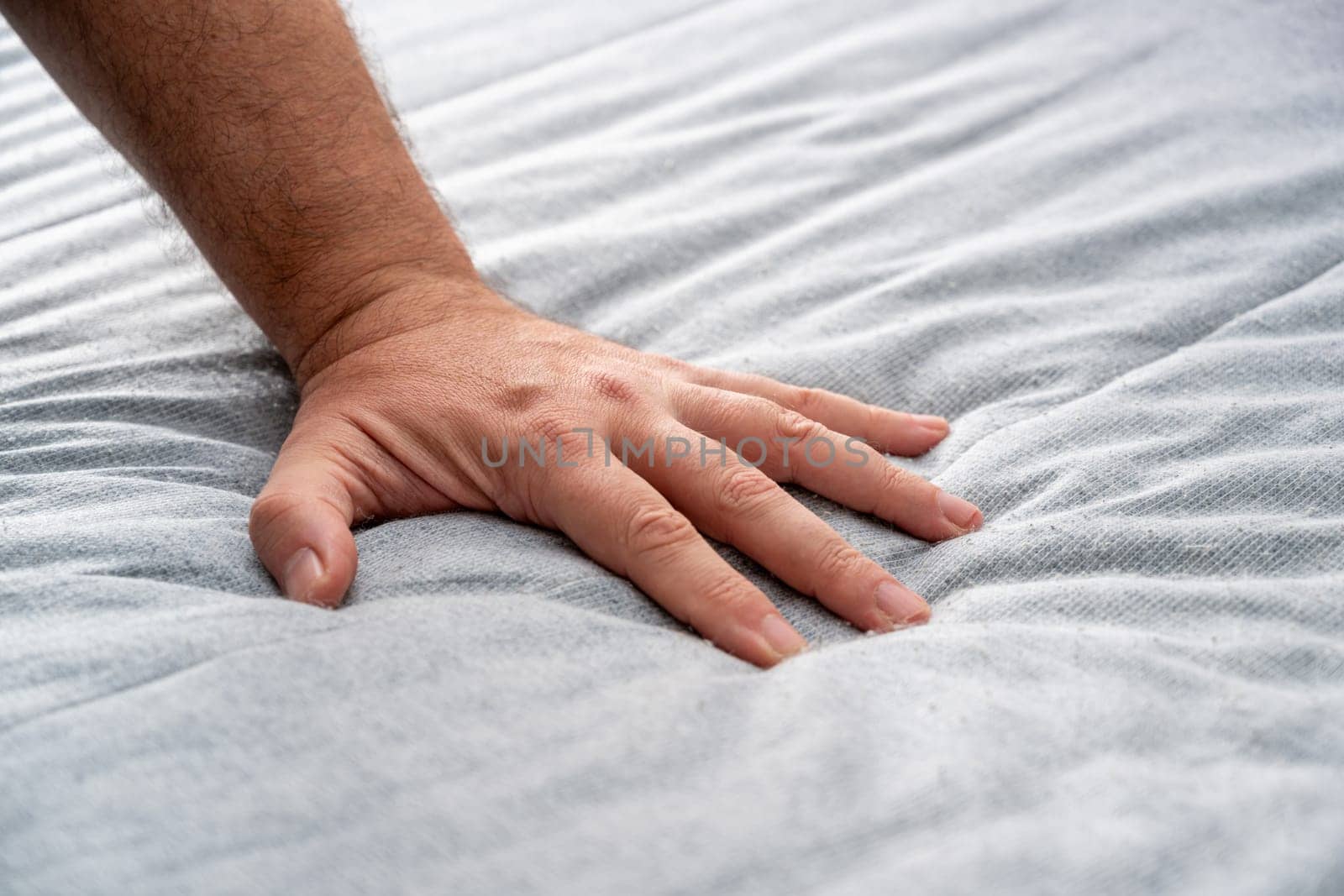 The man checks the quality and softness of the new mattress he will buy by pressing it with his hand