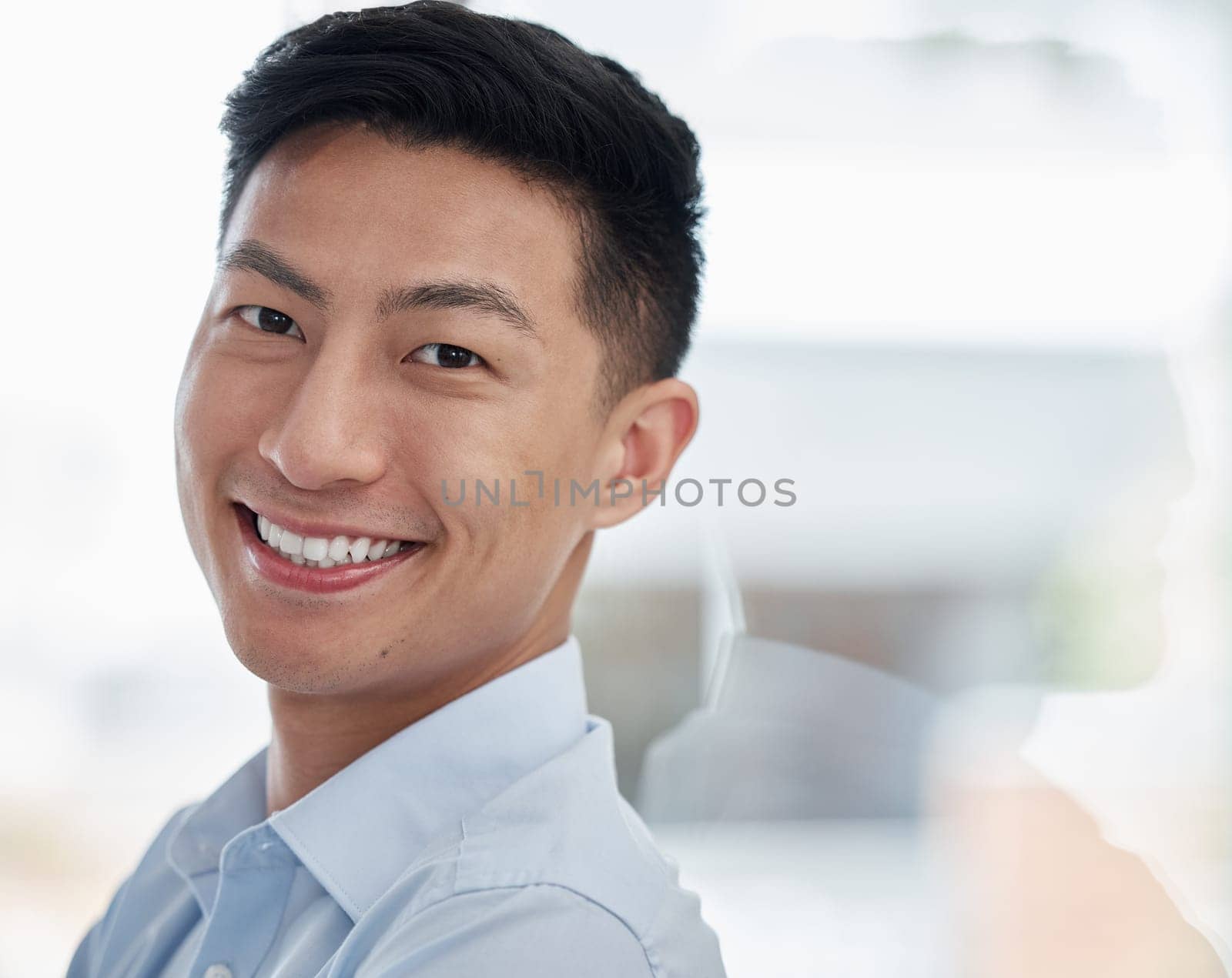 Asian man, portrait and business with smile for career ambition, entrepreneur or creative mindset at modern office. Face of young businessman leaning on glass wall in confidence for job or reflection.