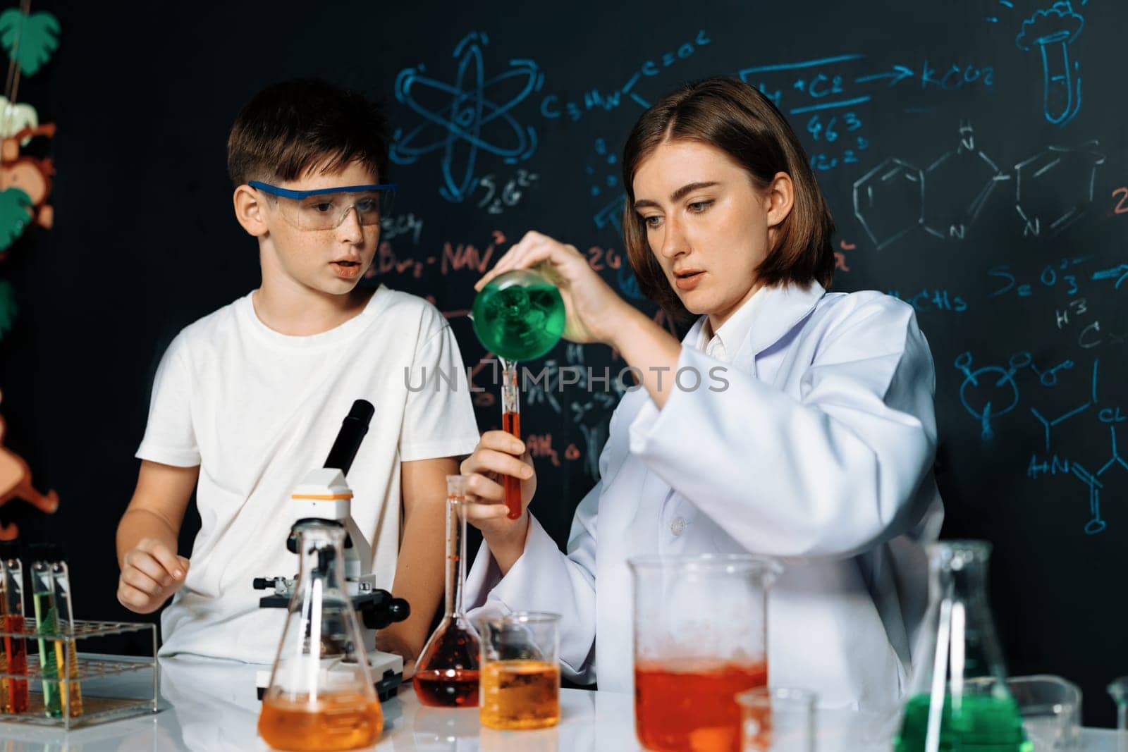 Teacher support schoolboy in laboratory. Schoolboy and teacher stand and experiment about science of chemistry in STEM class using liquid in glass container. Instructor mixing solution. Erudition.