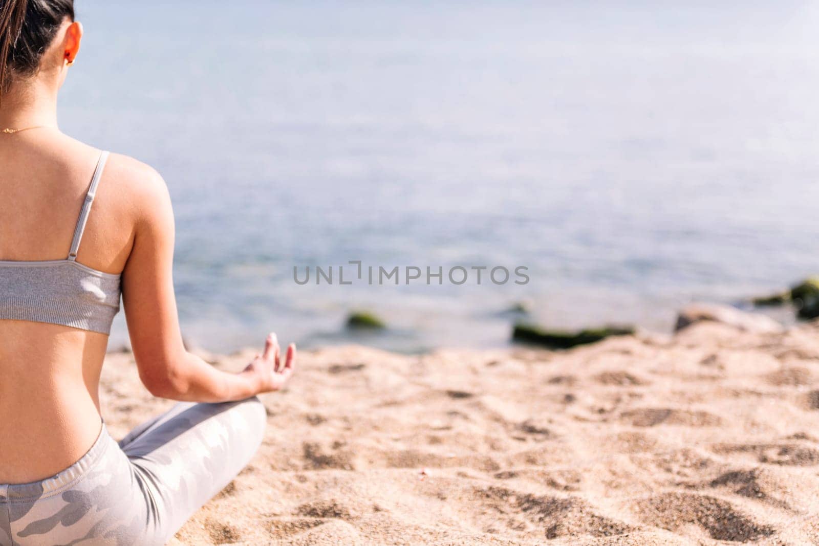 rear view of a young woman meditating at beach by raulmelldo