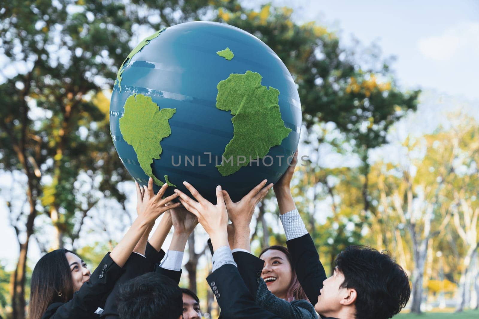 Earth day concept with big Earth globe held by group of asian business people team promoting environmental awareness to solve global warming with environmentally sustainability and ESG principle. Gyre