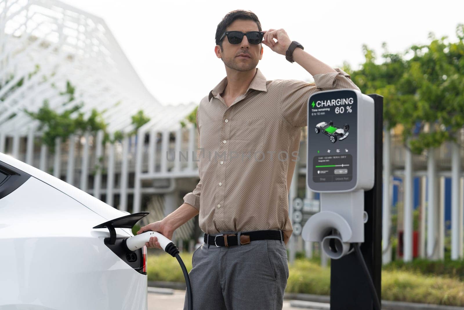 Young man put EV charger to recharge electric car battery. Expedient by biancoblue