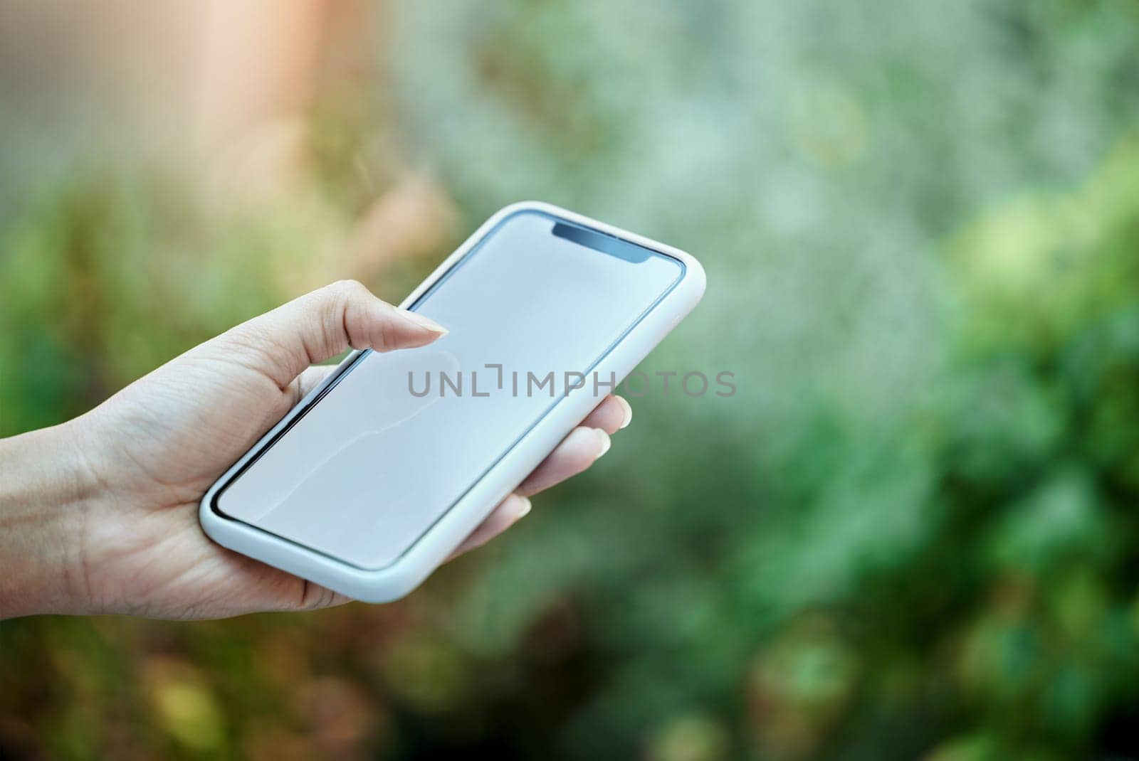 Mockup, mobile phone and hand of person in park for social media, online communication or browsing internet. Bokeh, scrolling and closeup of woman on smartphone for promotion, copy space or branding by YuriArcurs