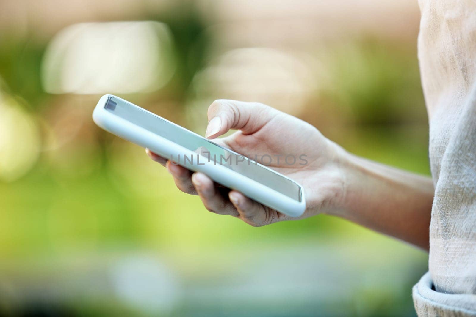 Person, hand typing and mobile phone in park for social media, communication or networking outdoors. Bokeh, scrolling and closeup of woman with smartphone for connection, browsing internet or contact by YuriArcurs