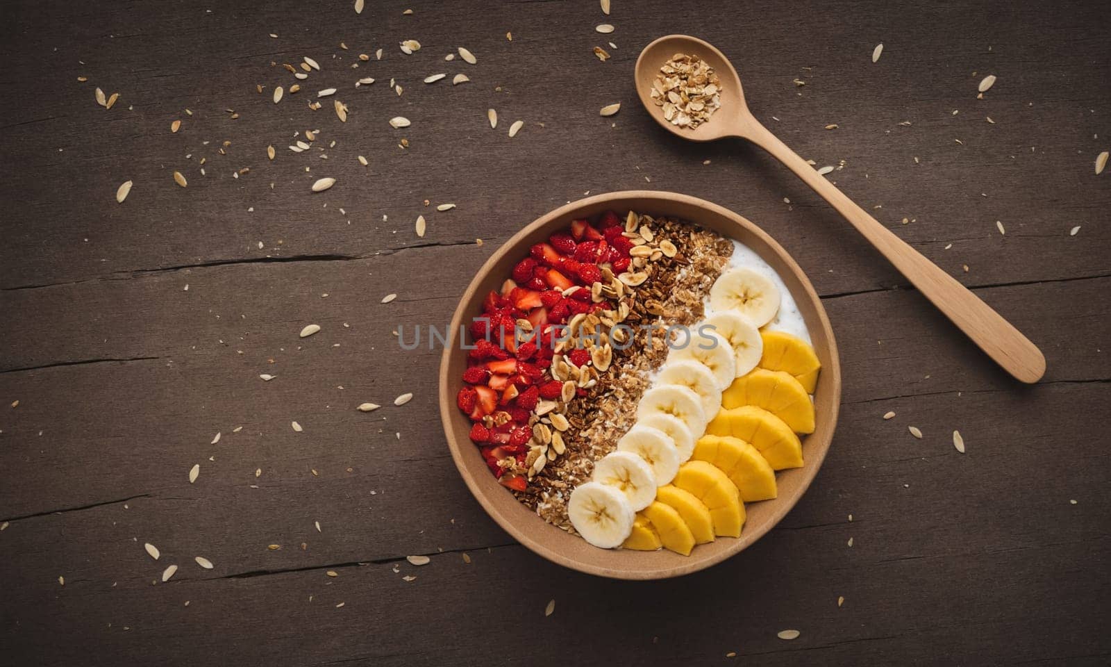 Colorful smoothie bowl in a coconut shell, topped with banana, goji berries, granola, and coconut flakes.