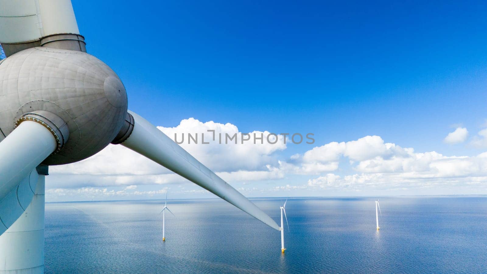 A lone wind turbine stands tall in the middle of the vast ocean, harnessing the power of the wind to create clean and renewable energy for the surrounding area by fokkebok