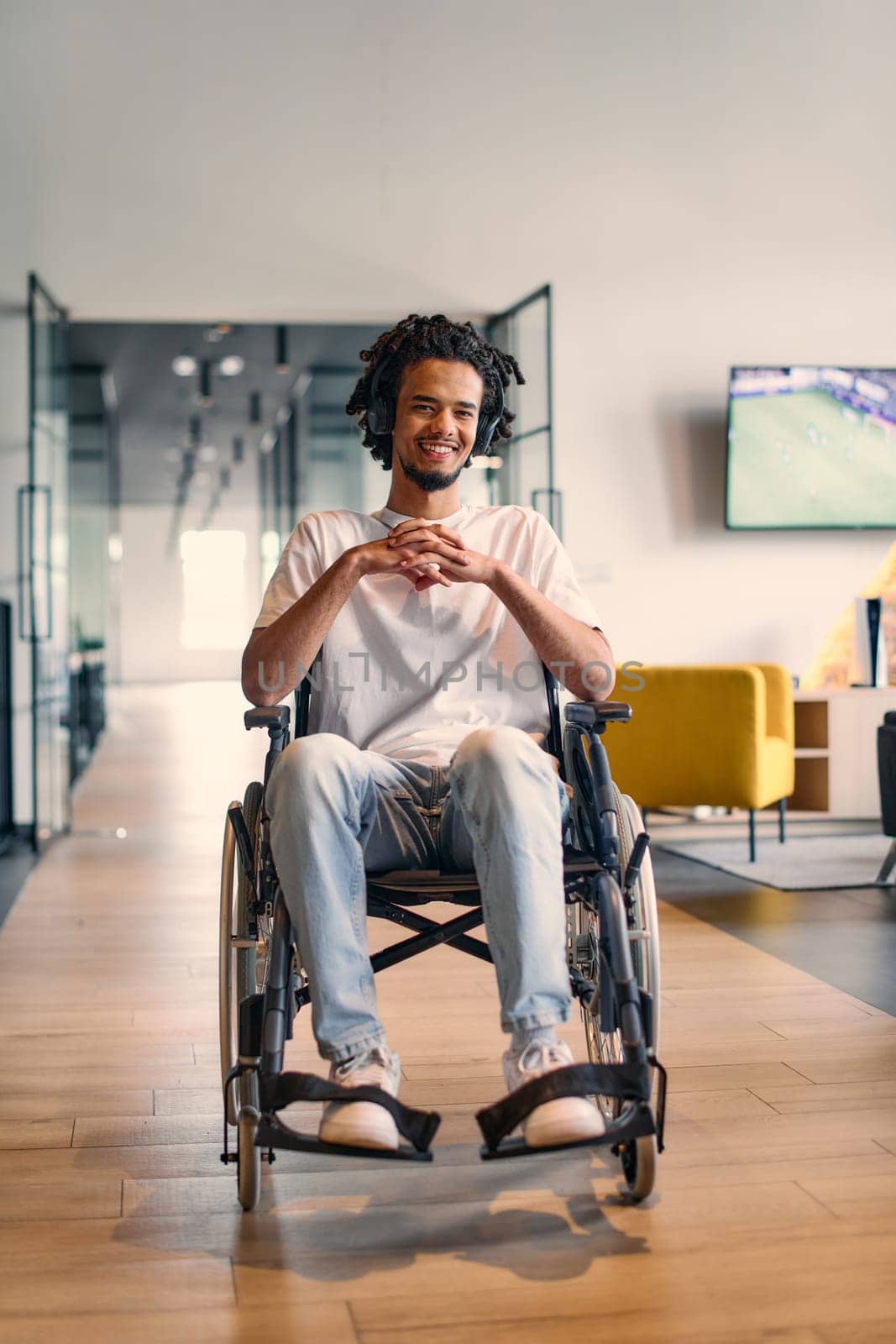 An African-American young entrepreneur in a wheelchair is surrounded by his business colleagues in a modern office setting, embodying diversity and collaboration in the workplace.