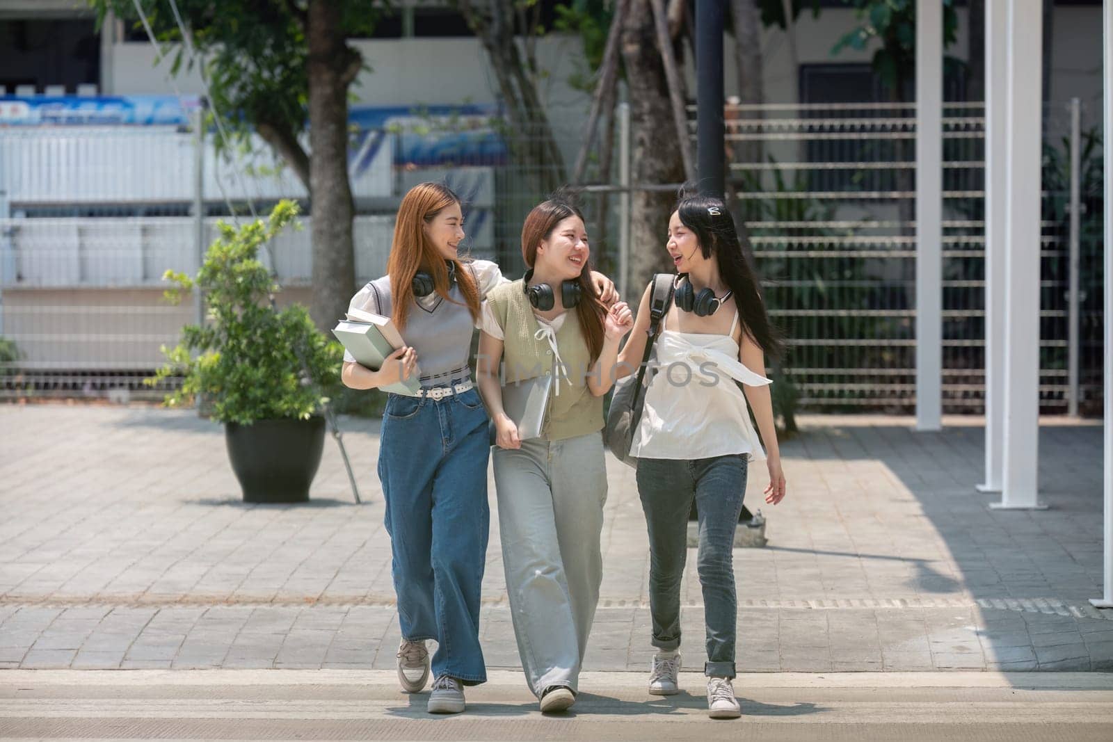 College friends walk to class together. University student in campus talk and have fun outdoors.