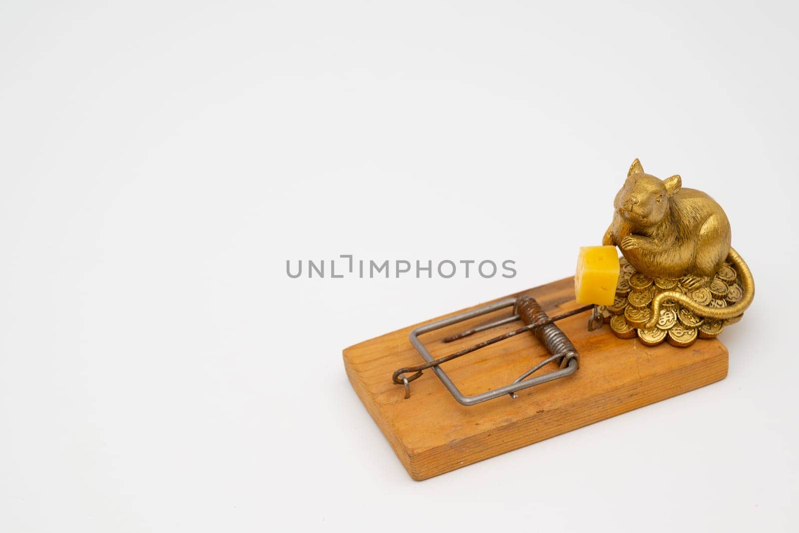 figurine of a rat near cheese in an old mousetrap