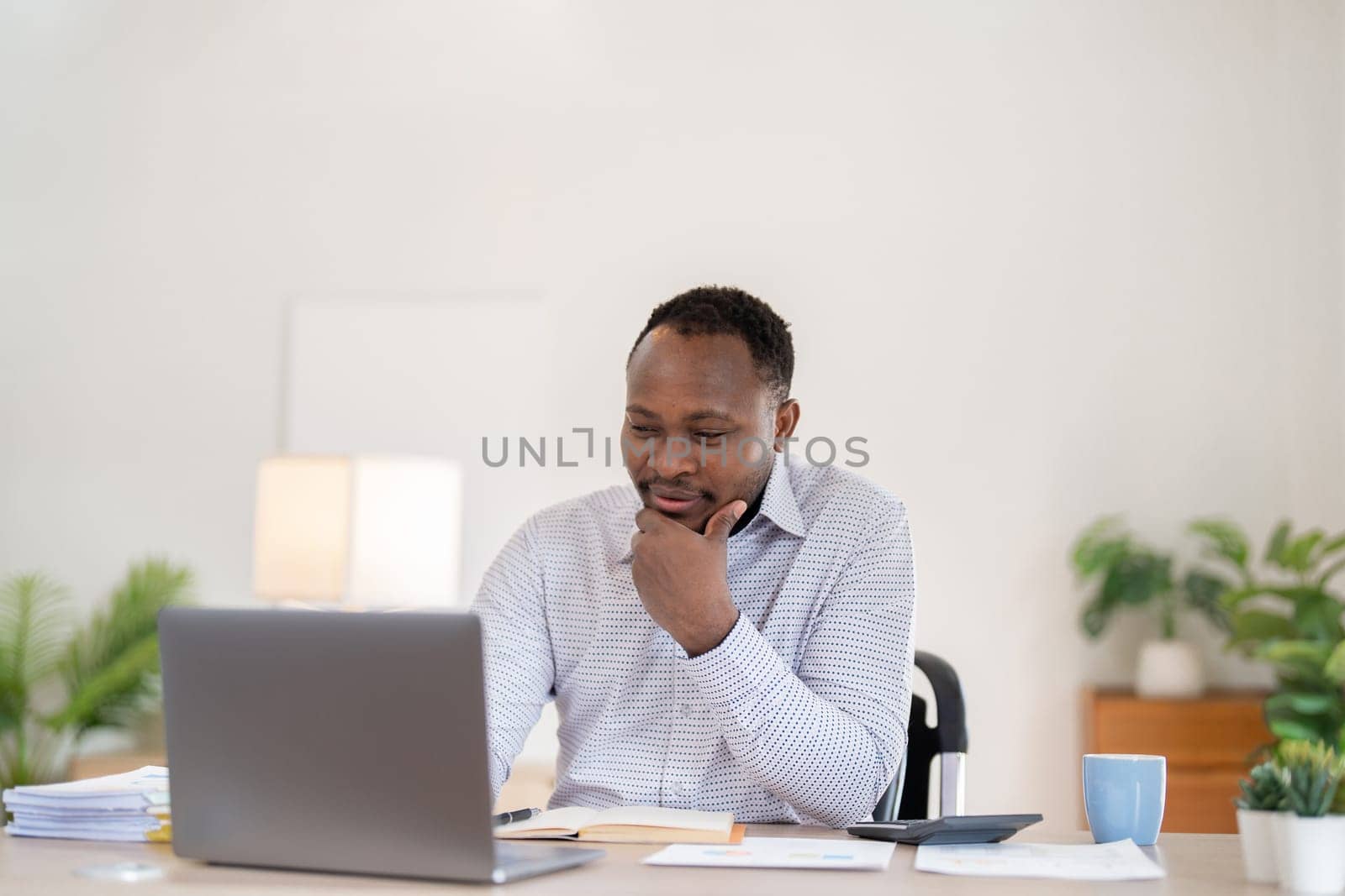 African American businessman working with laptop Take notes on documents in the office and prepare performance analysis reports..