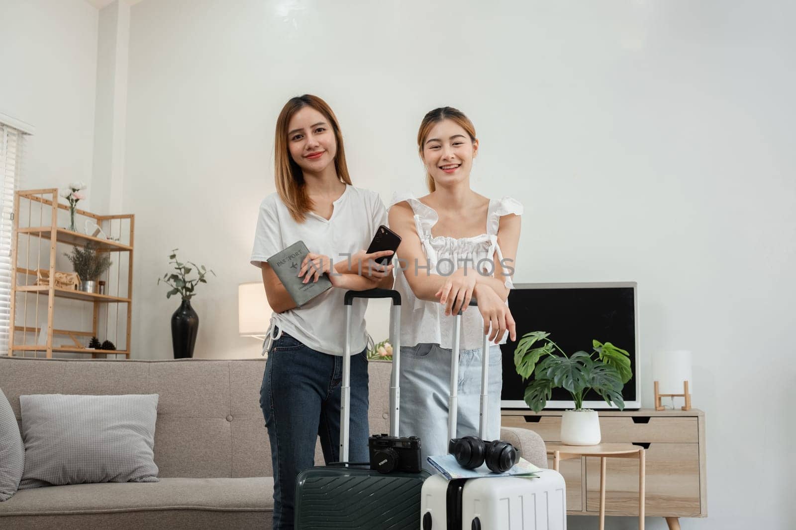 Two female friends with suitcases and passports getting ready for a weekend away together. by wichayada