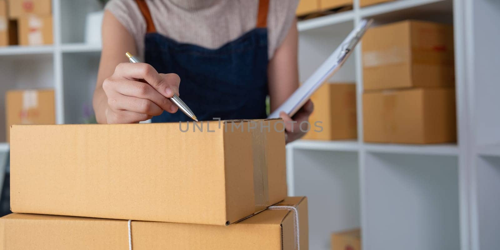 SME business entrepreneurs small in Asia Write shipping information on a cardboard box in home office. Small business operators preparing to ship to customer by wichayada