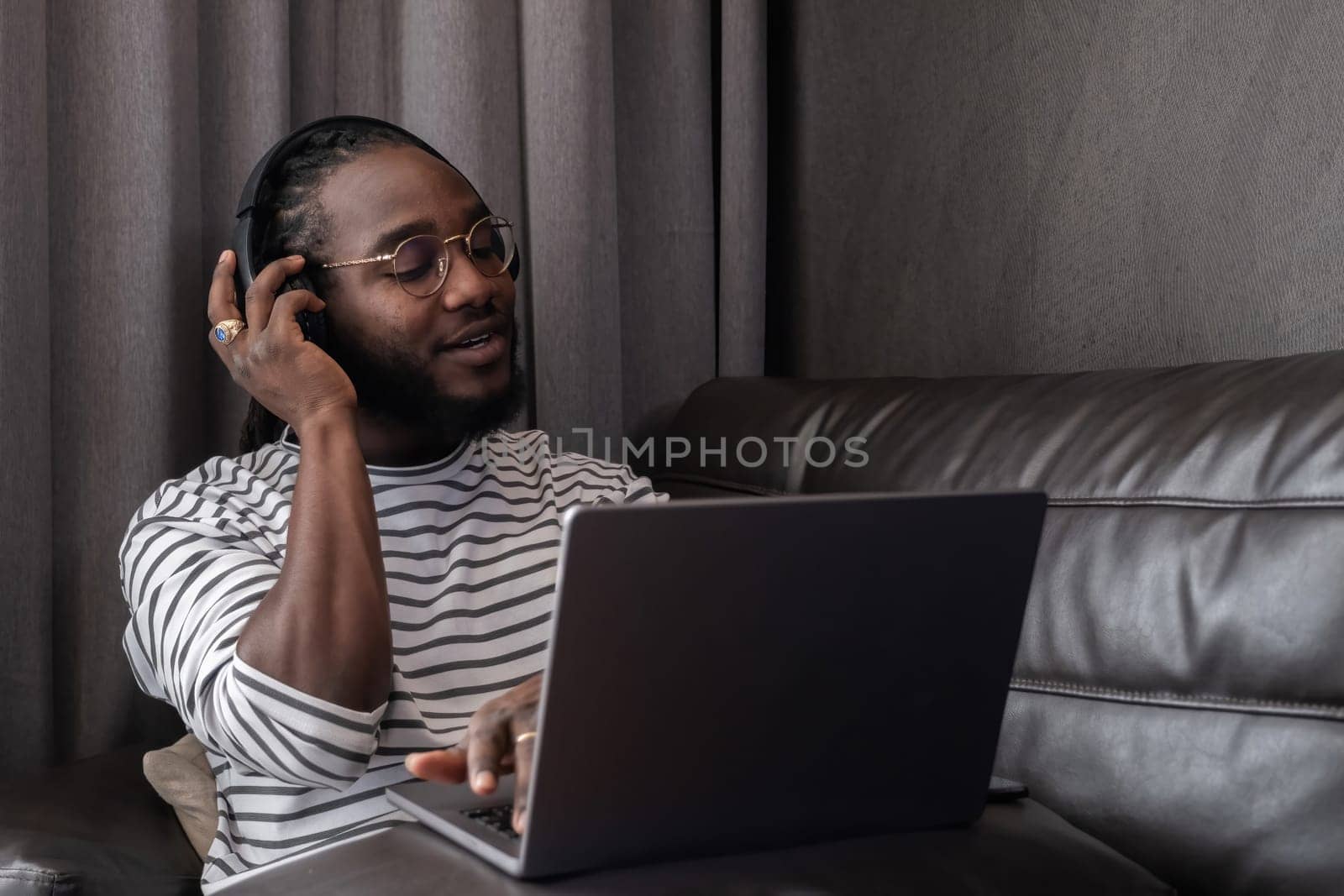 Young African American businessman spends his weekend working from home using his laptop in the living room..