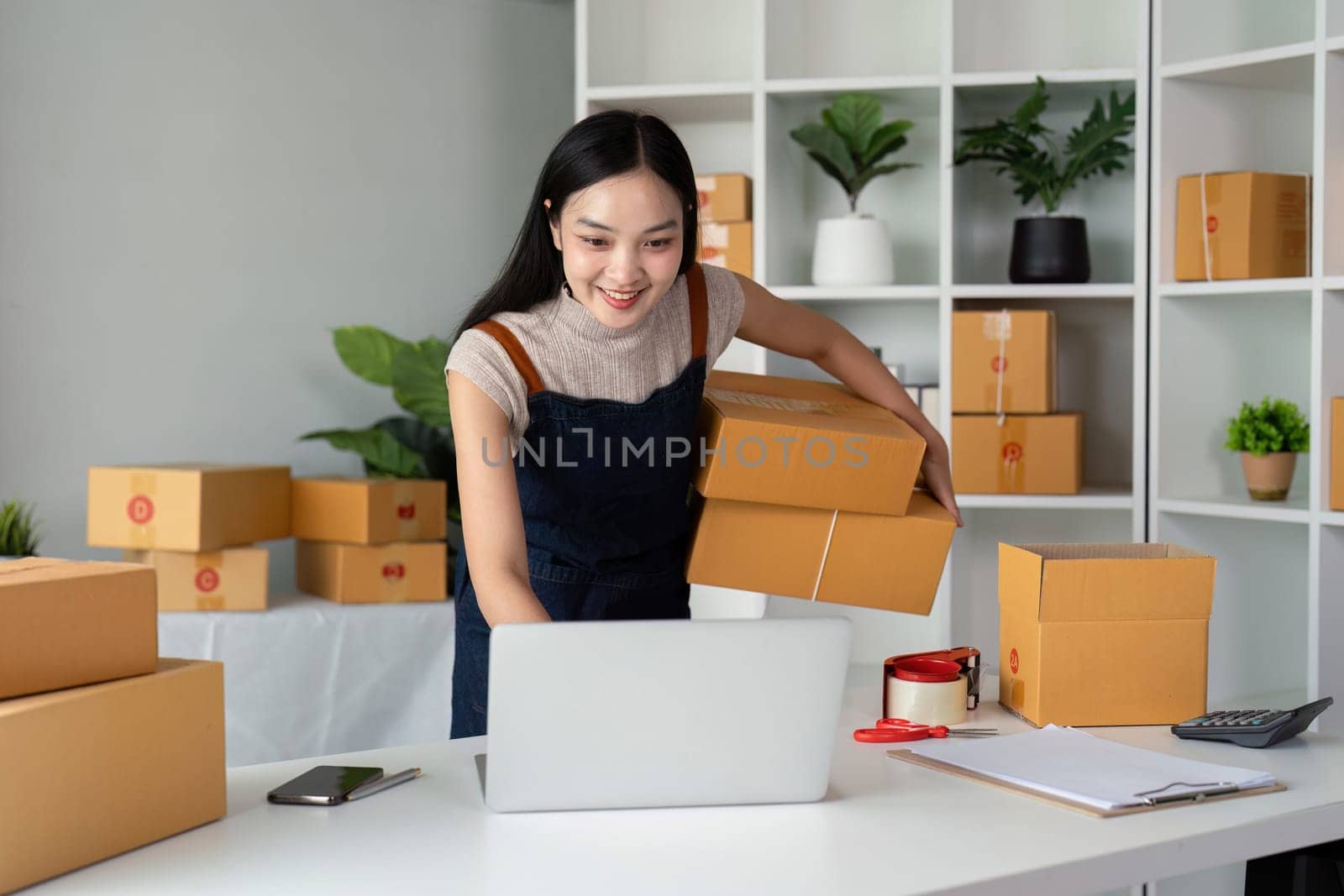 Woman asian in an online store check the customer address and package information on the laptop. Online shopping concept.