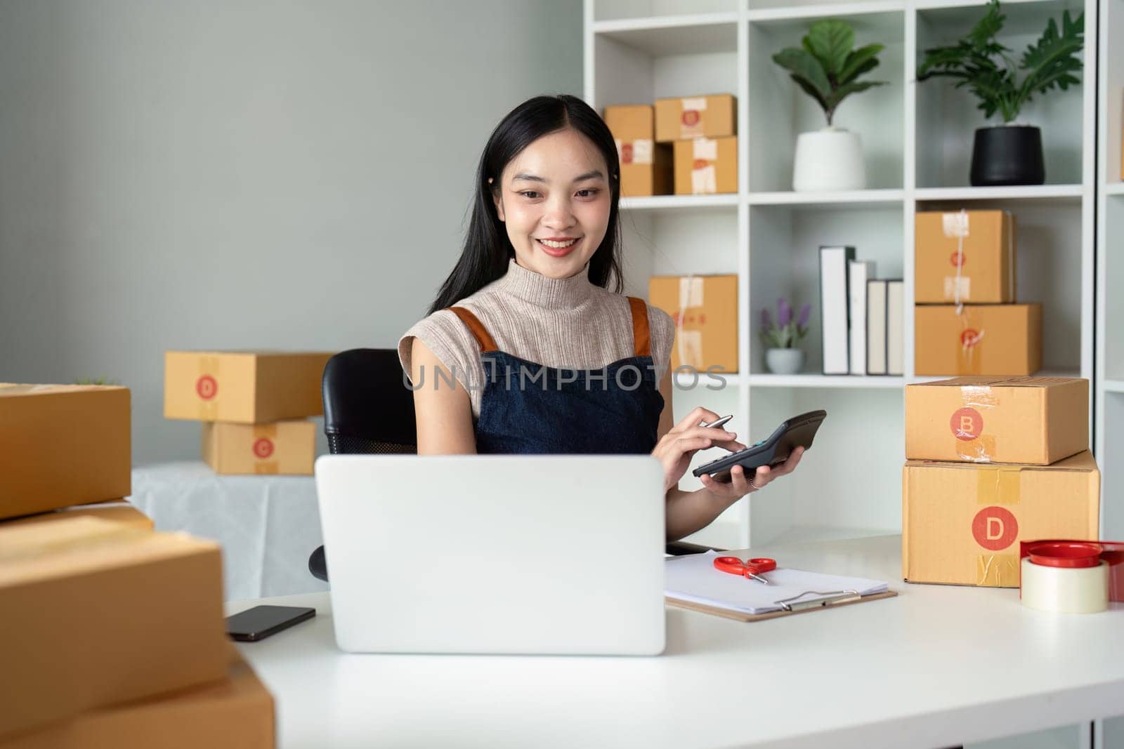 Young business woman asian working online ecommerce shopping at her shop. Young woman sell prepare parcel box of product for deliver to customer. Online selling by nateemee