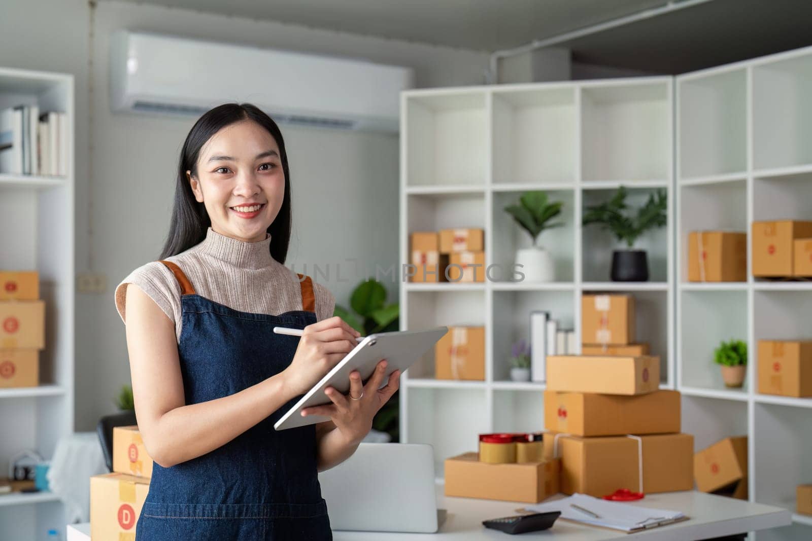 Young business woman asian working online ecommerce shopping at her shop. Young woman sell prepare parcel box of product for deliver to customer. Online selling by nateemee