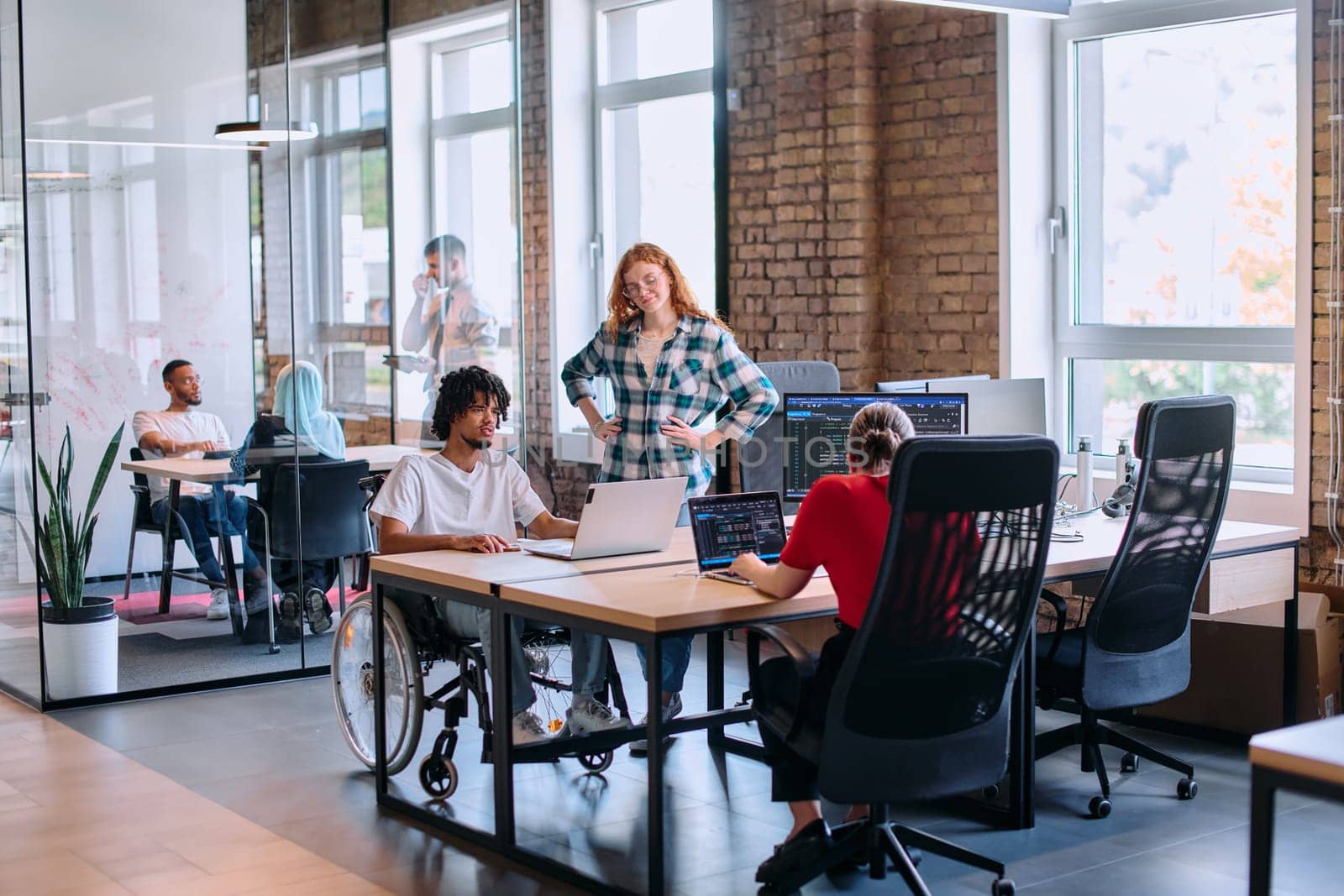 A diverse group of business professionals collaborates in a modern startup coworking center, utilizing a mix of paper-based and technological tools such as mobile phones and computers .