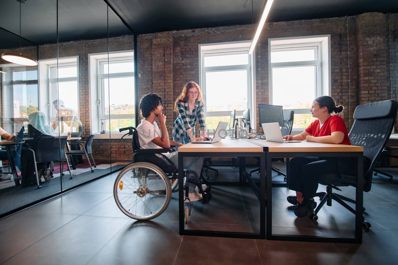 A diverse group of business professionals collaborates in a modern startup coworking center, utilizing a mix of paper-based and technological tools such as mobile phones and computers .