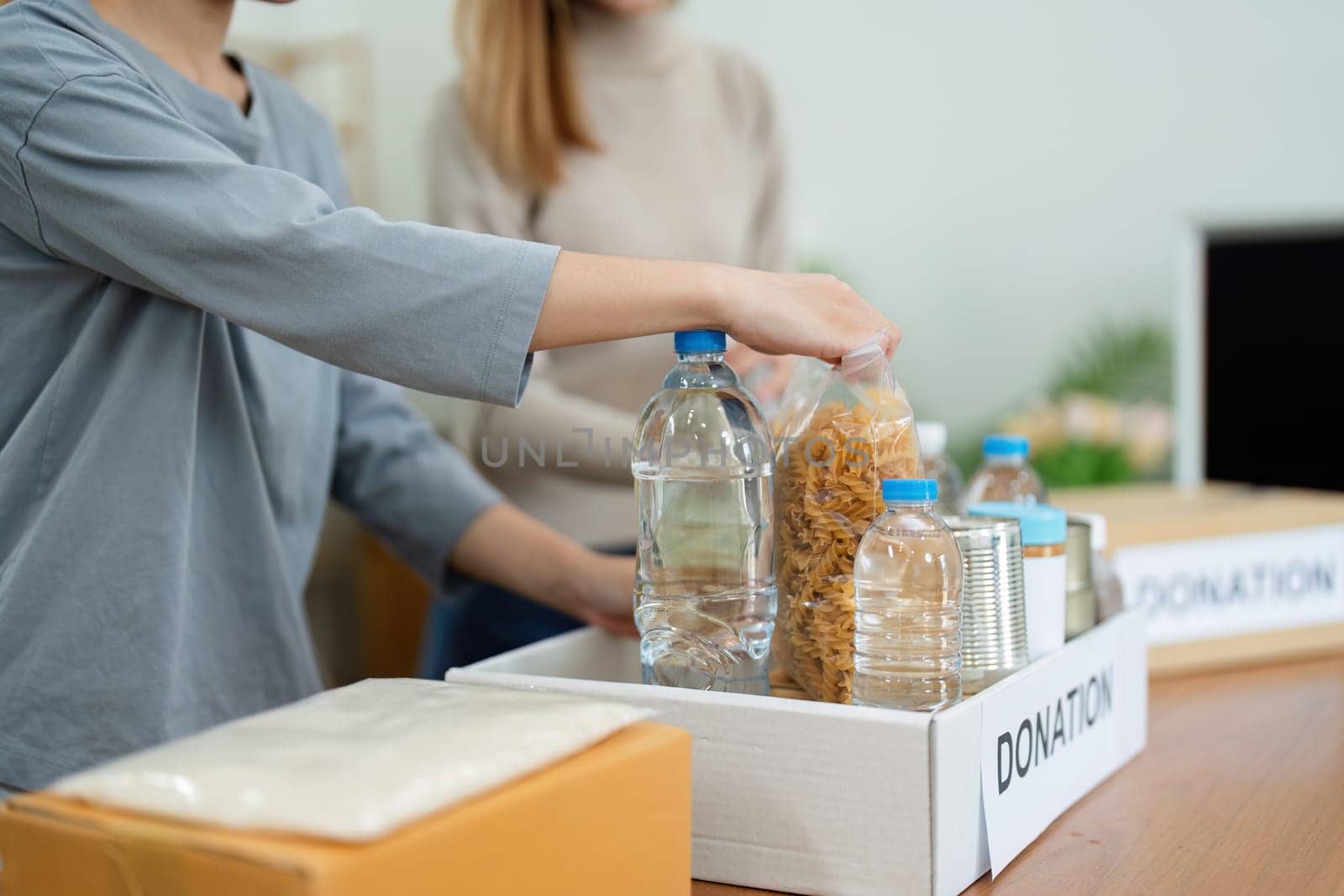 charity, donation and volunteering concept. Volunteer prepare foodstuff box containing food to donate to people poor, disaster victim at home.