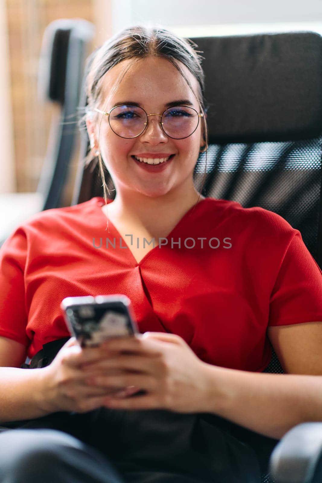 A businesswoman resting on a short break from work in a modern startup coworking center, using her smartphone to unwind and recharge.