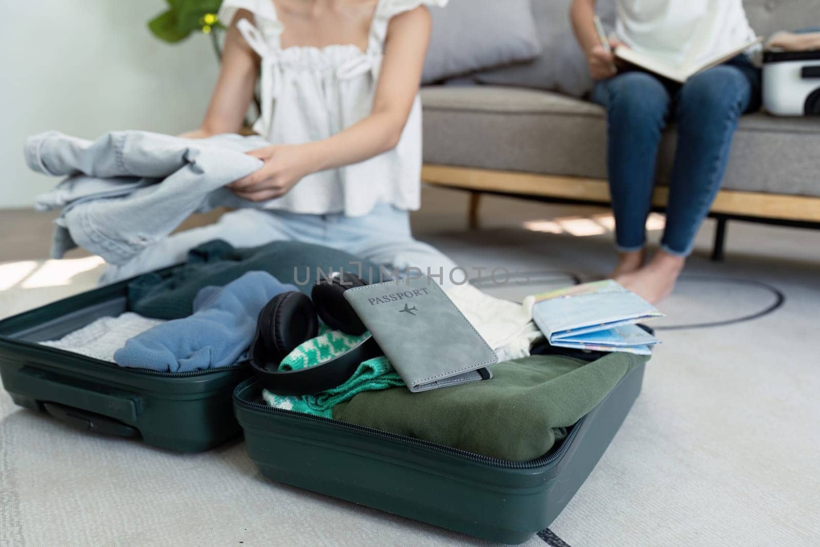 A woman is sitting on the floor with her luggage open. She is looking at her clothes and passport