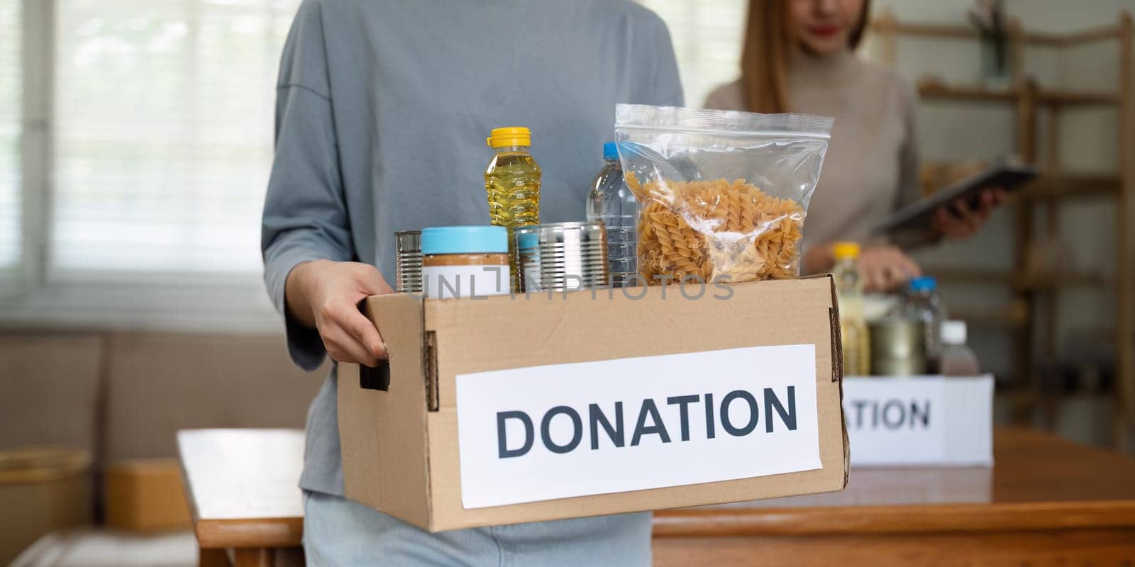 charity, donation and volunteering concept. Volunteer prepare foodstuff box containing food to donate to people poor, disaster victim at home.