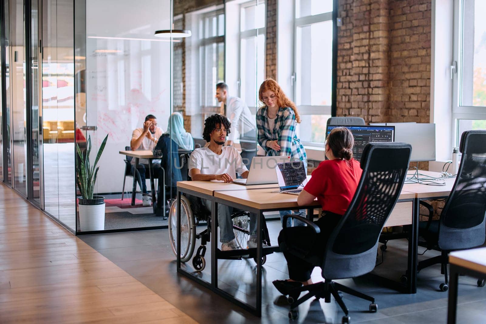 A diverse group of business professionals collaborates in a modern startup coworking center, utilizing a mix of paper-based and technological tools such as mobile phones and computers .