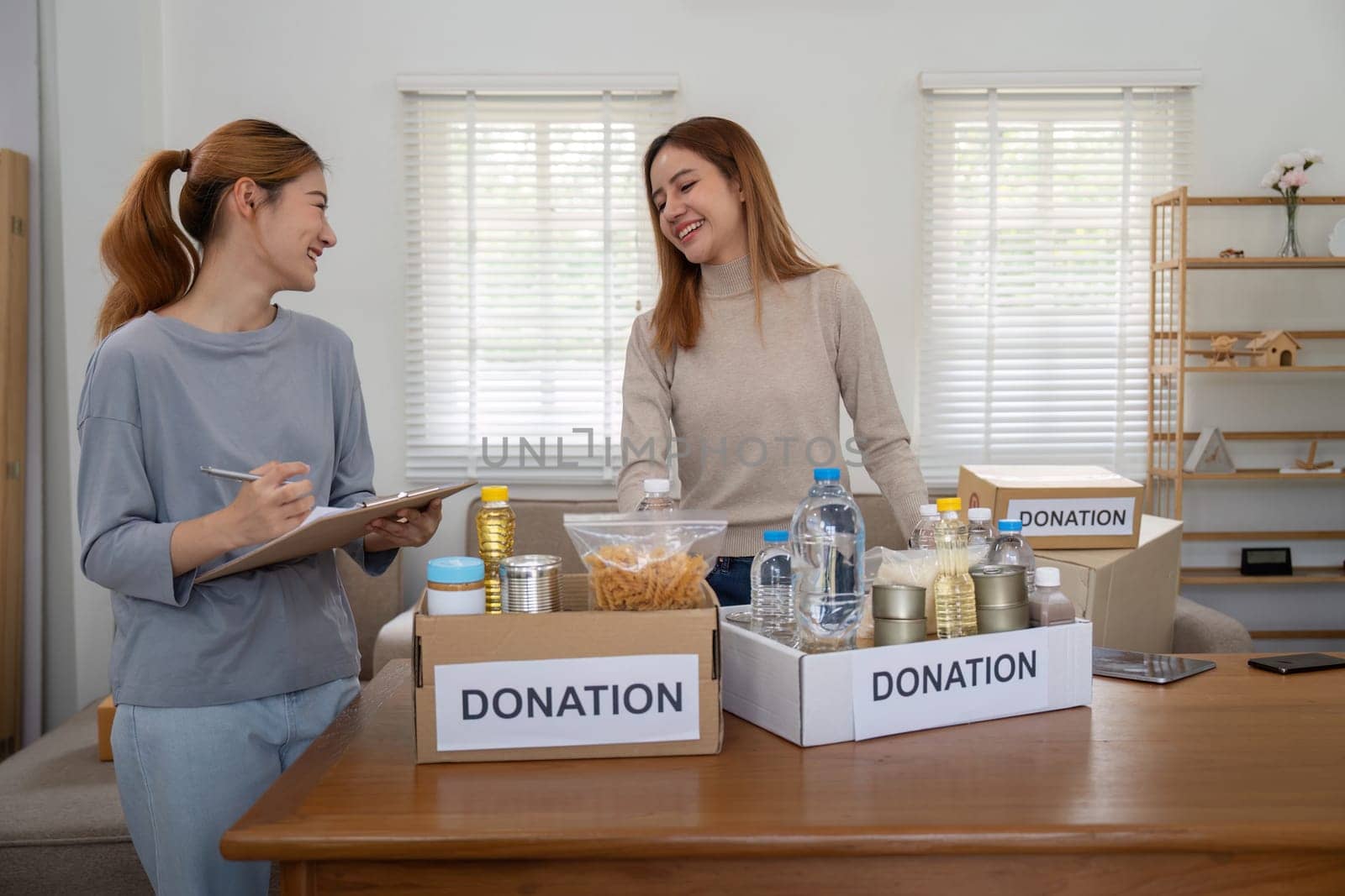 Donation and two woman volunteer asian of happy packing food in box at home. Charity.