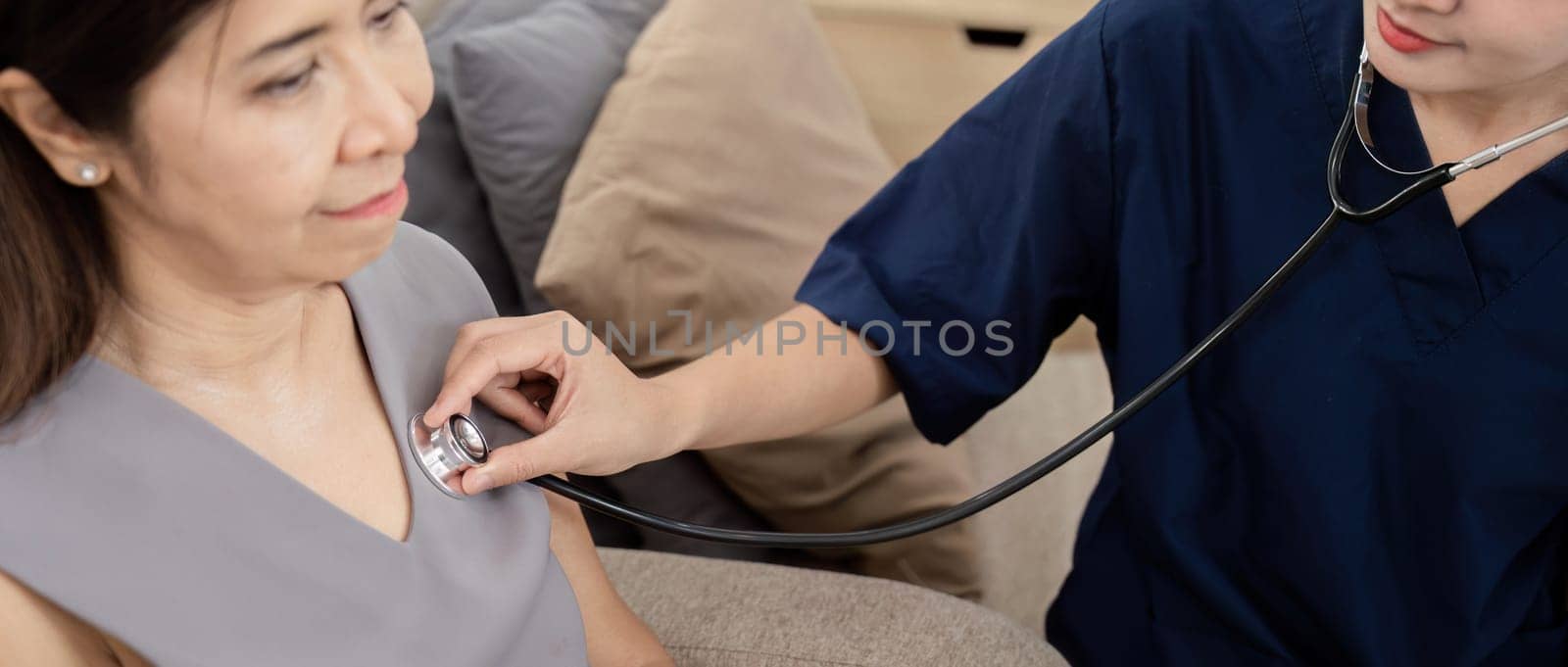 Elderly woman asian patient are check up health while a woman doctor or caregiver woman use a stethoscope to hear heart rate. elderly healthcare concept.