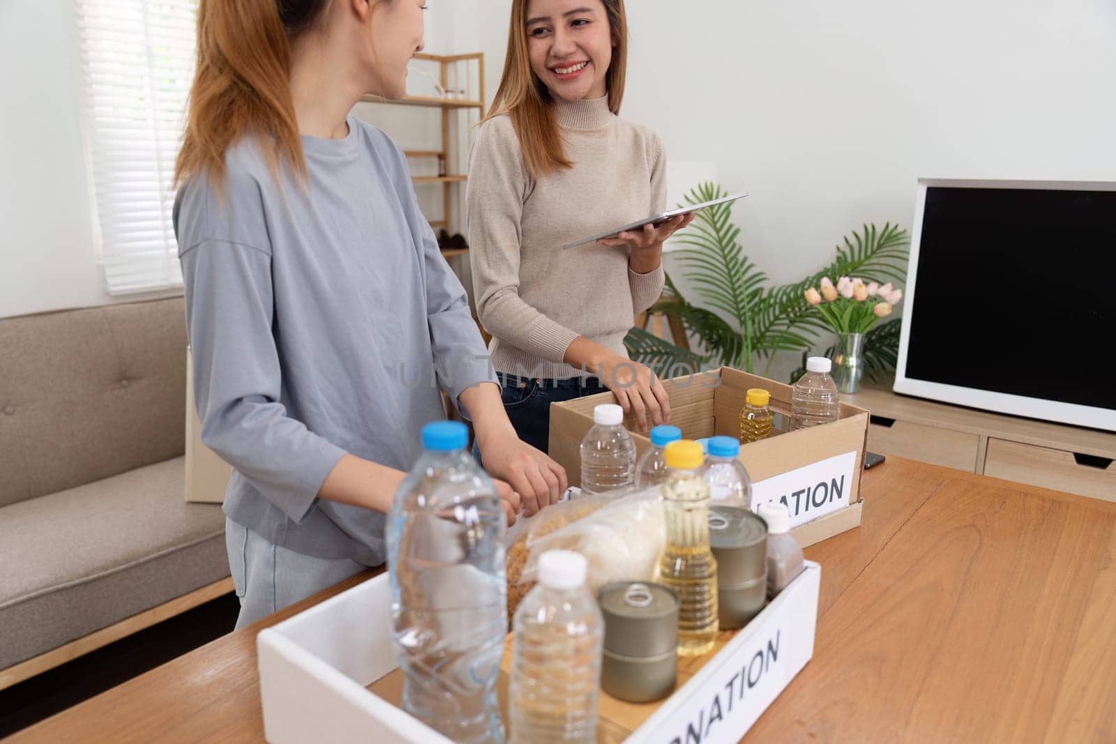 Woman with charity box and group of volunteers at assistance center. Charity, donation, and volunteering concept.