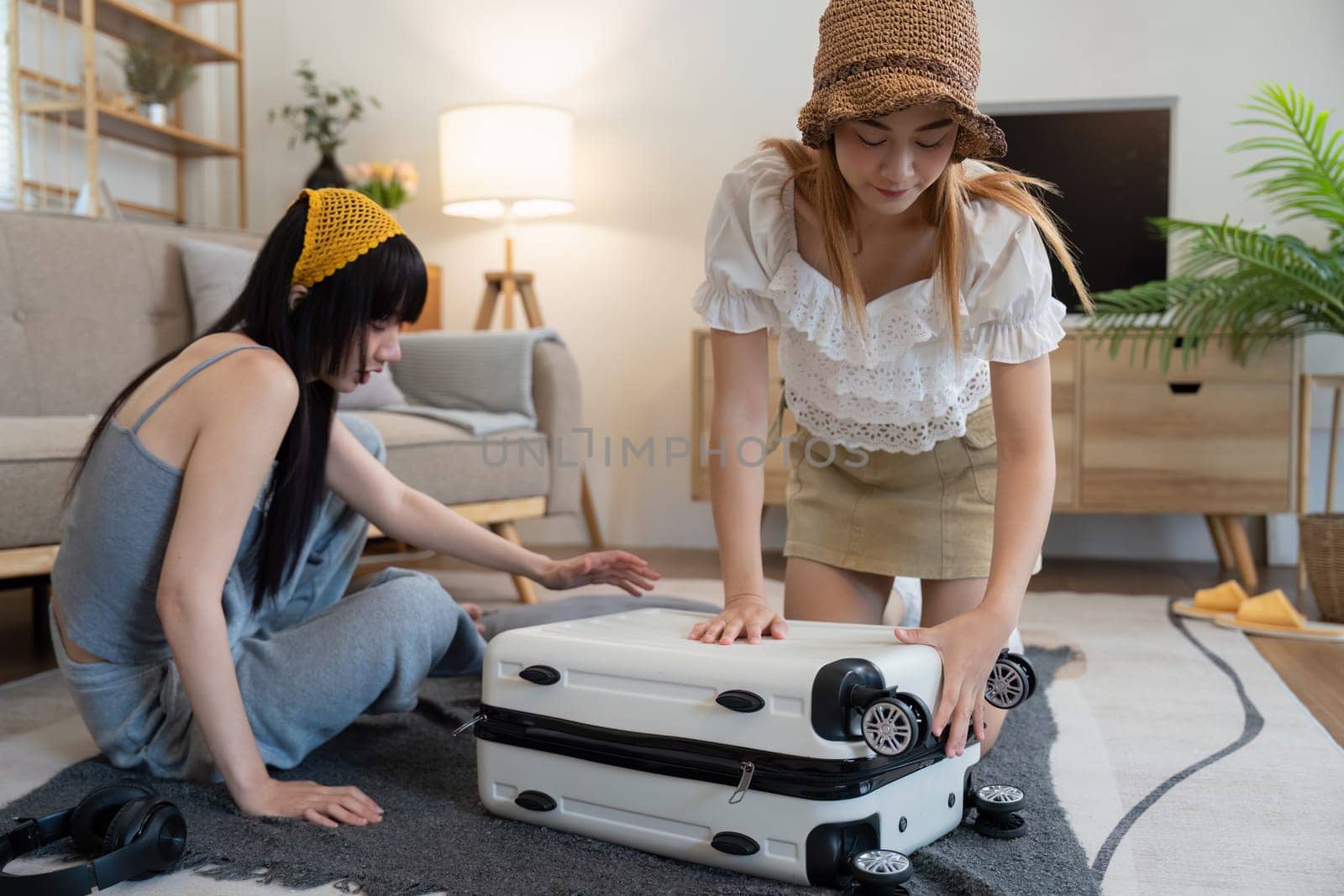 Friendship. Travel together. Two asian young woman friends packing for summer vocation. preparation planning concept by nateemee