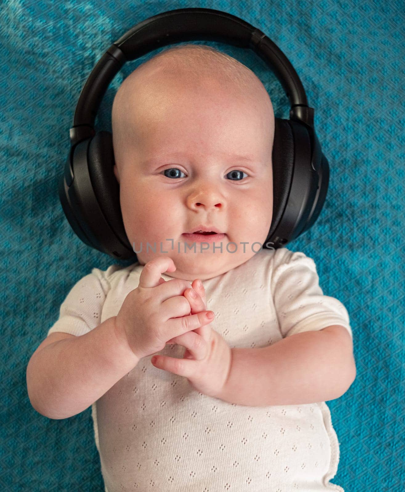 Little boy on blue blanket background with headphones
